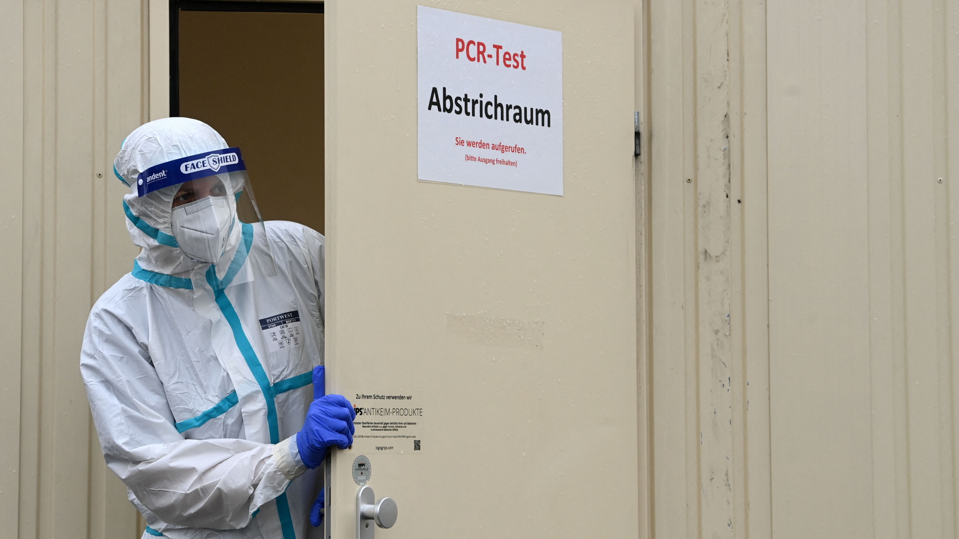 Eine Mitarbeiterin eines Corona-Testzentrums bei München schaut aus einer offenen Tür heraus
