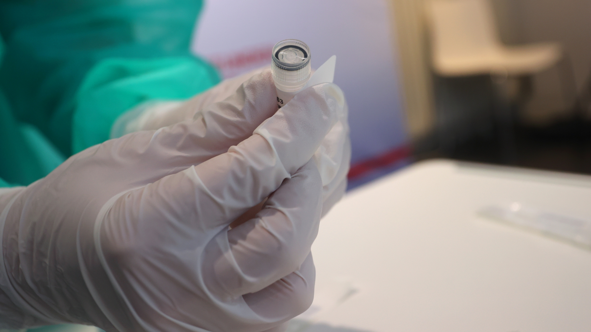 Eine medizinische Assistentin hält in einer Teststation ein Röhrchen mit einer Abstrichprobe für einen PCR-Test