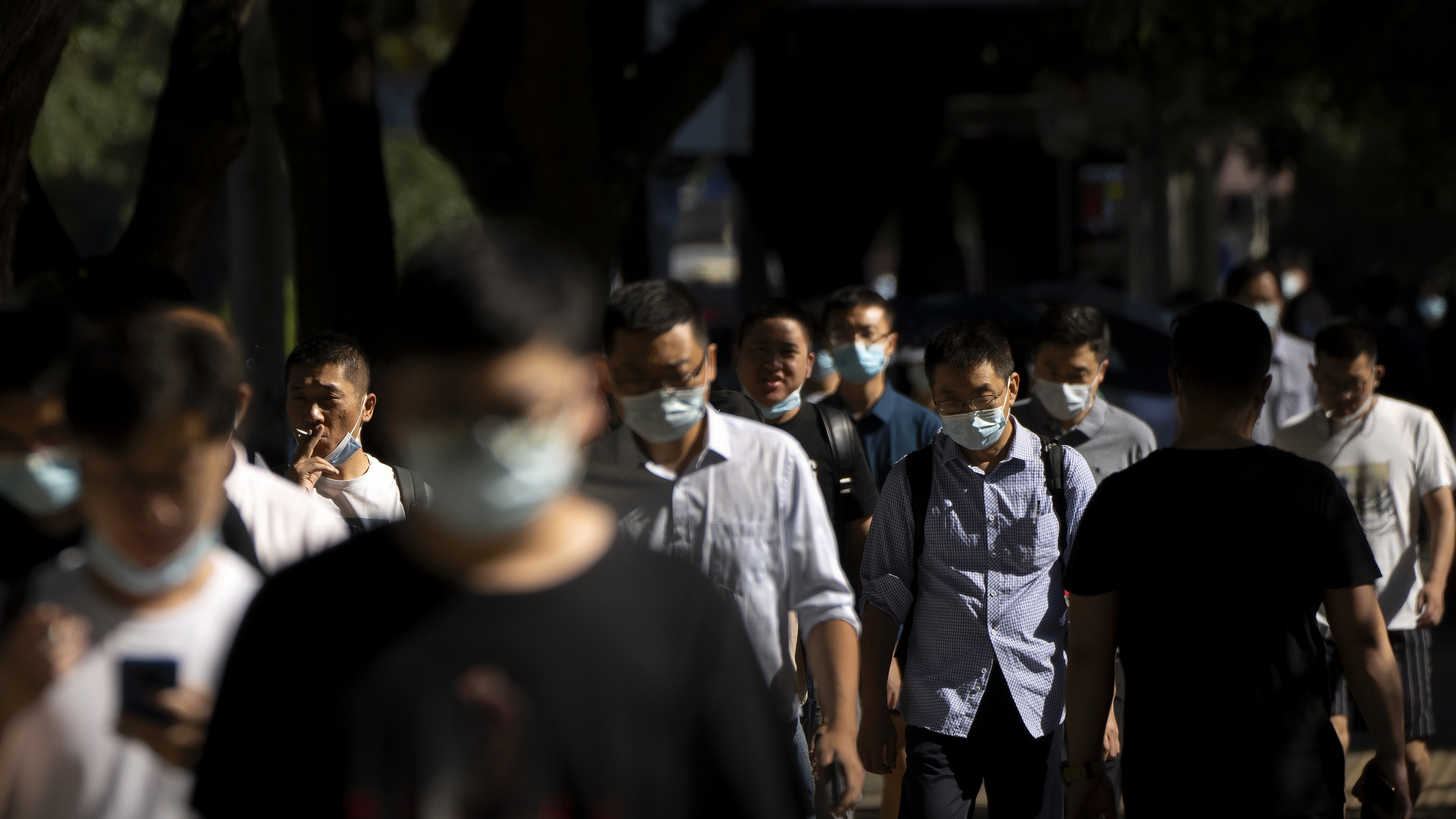 Pendler mit Gesichtsmasken laufen eine Straße in Peking entlang | dpa