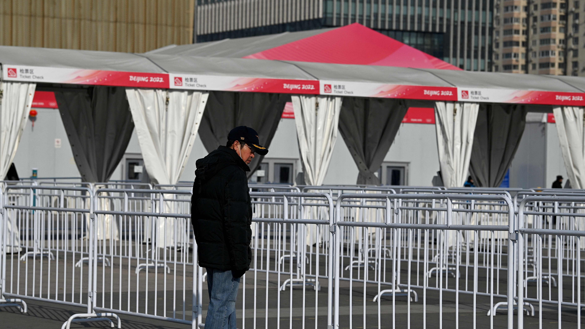 Ein Mann steht in Peking (China) vor einer Absperrung an einer Sportstätte der Olympischen Winterspiele 2022 | AFP