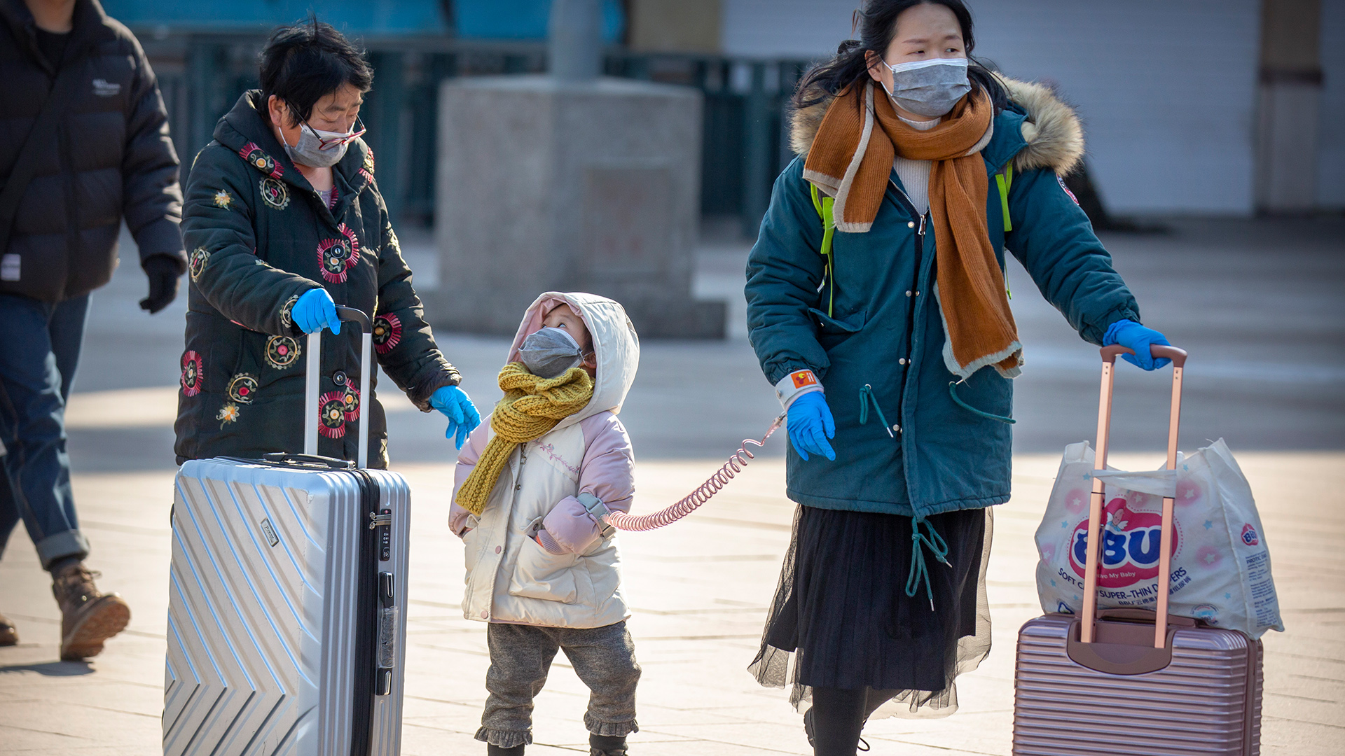 Reisende am Bahnhof in Peking mit Rollkoffern tragen Mundschutz, China | dpa