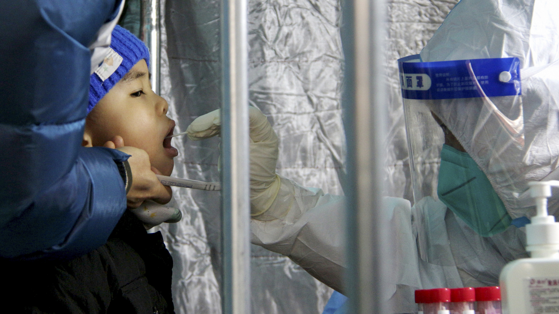 Ein Mitarbeiter entnimmt einen Rachenabstrich bei einem Kind in einem Pekinger Wohngebiet im Bezirk Fengtai.