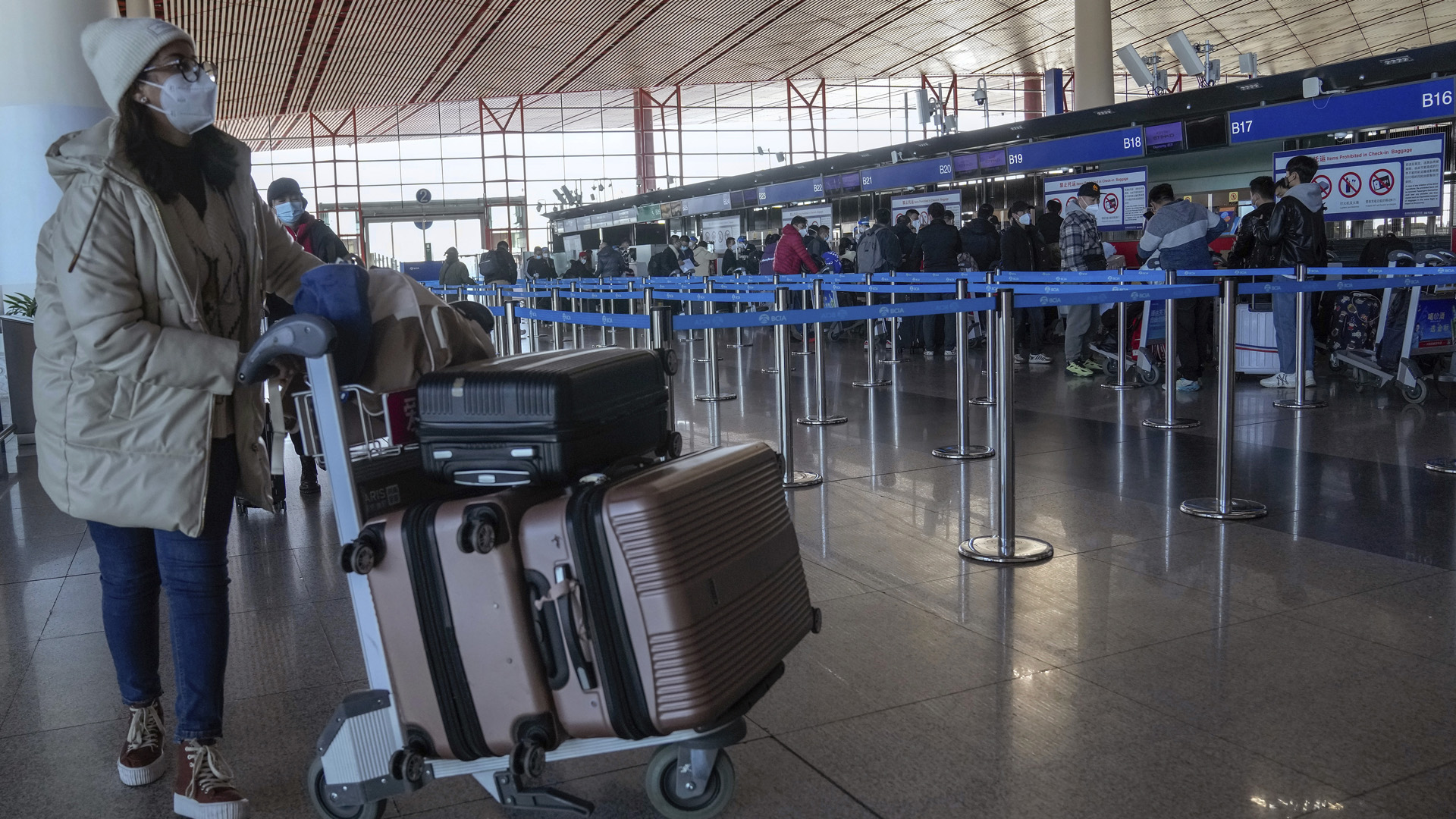 Eine Reisende kommt am Check-in-Schalter für internationale Flüge auf dem Beijing Capital International Airport in Peking an | picture alliance/dpa/AP