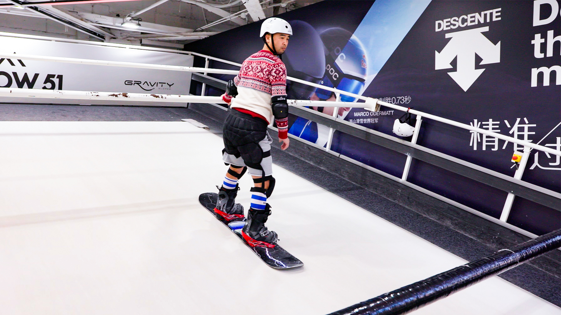 Ein Snowboard-Fahrer mit Schutzausrüstung fährt in einer Wintersport-halle in Peking eine Rampe bergab. | ARD Peking