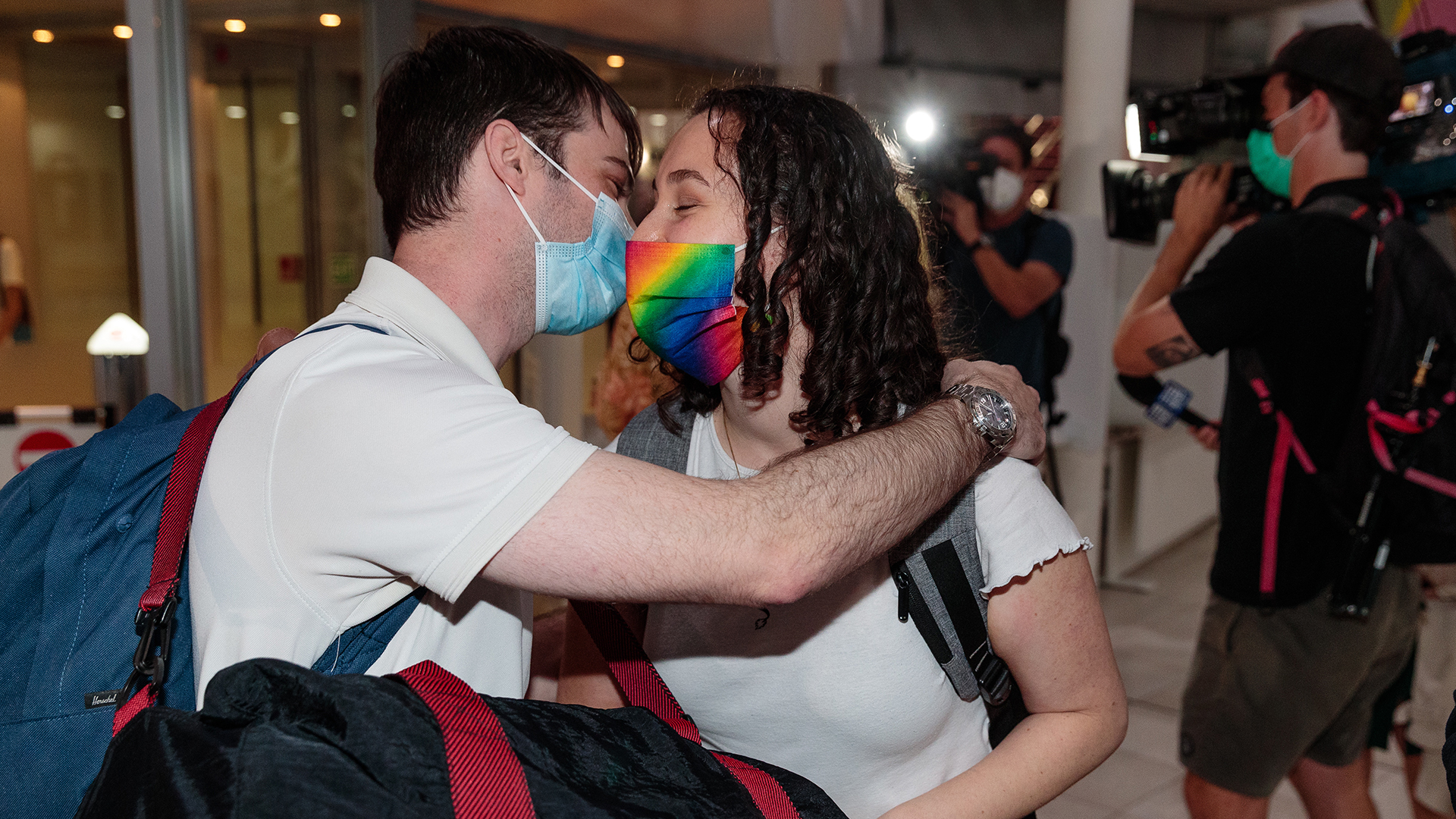 Zwei Menschen mit Mund-Nasen-Schutz küssen sich am Flughafen in Perth. | EPA