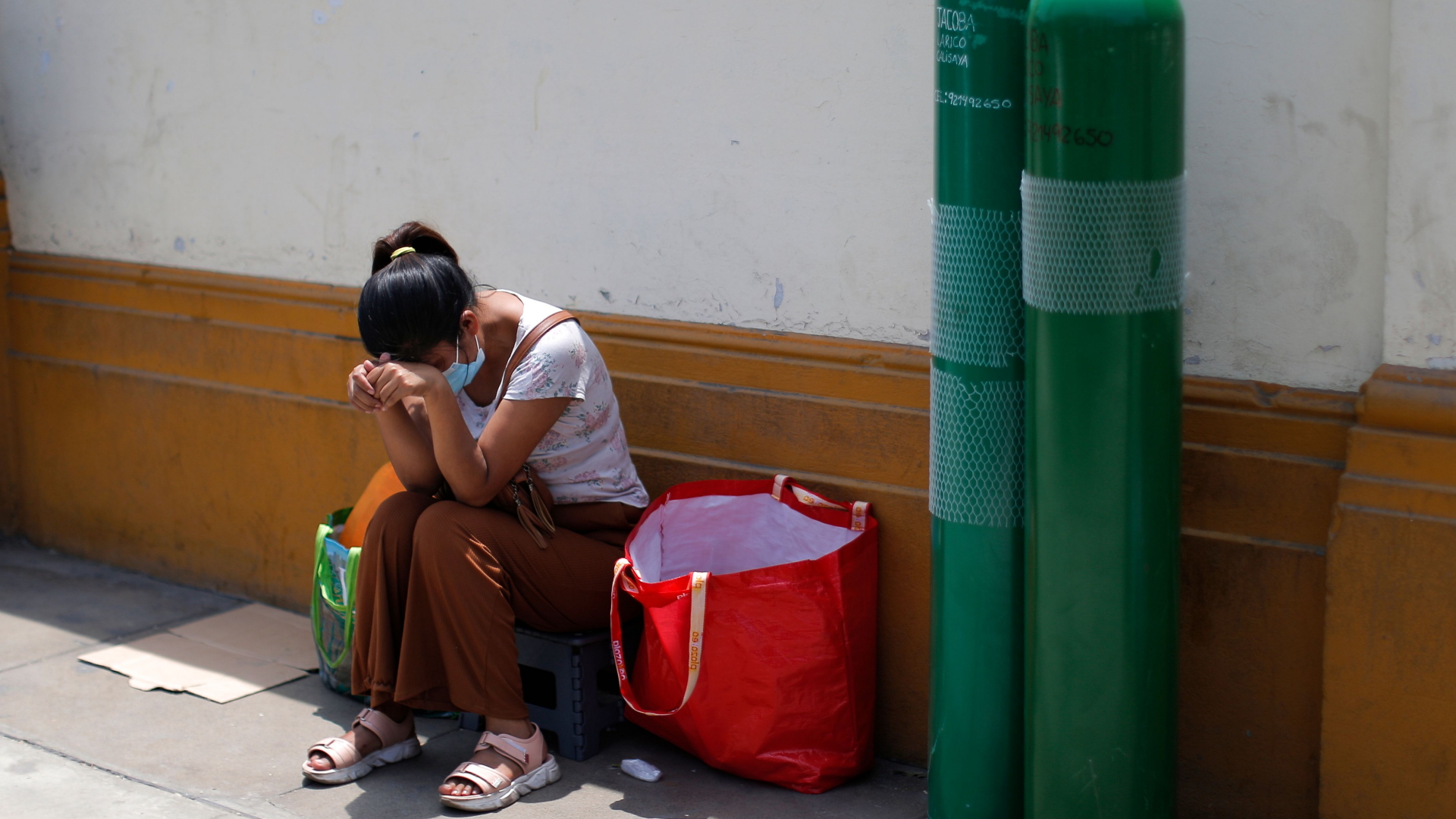 Frau in Lima (Peru) wartet darauf, dass Behältnisse mit medizinischem Sauerstoff nachgefüllt werden. | AFP