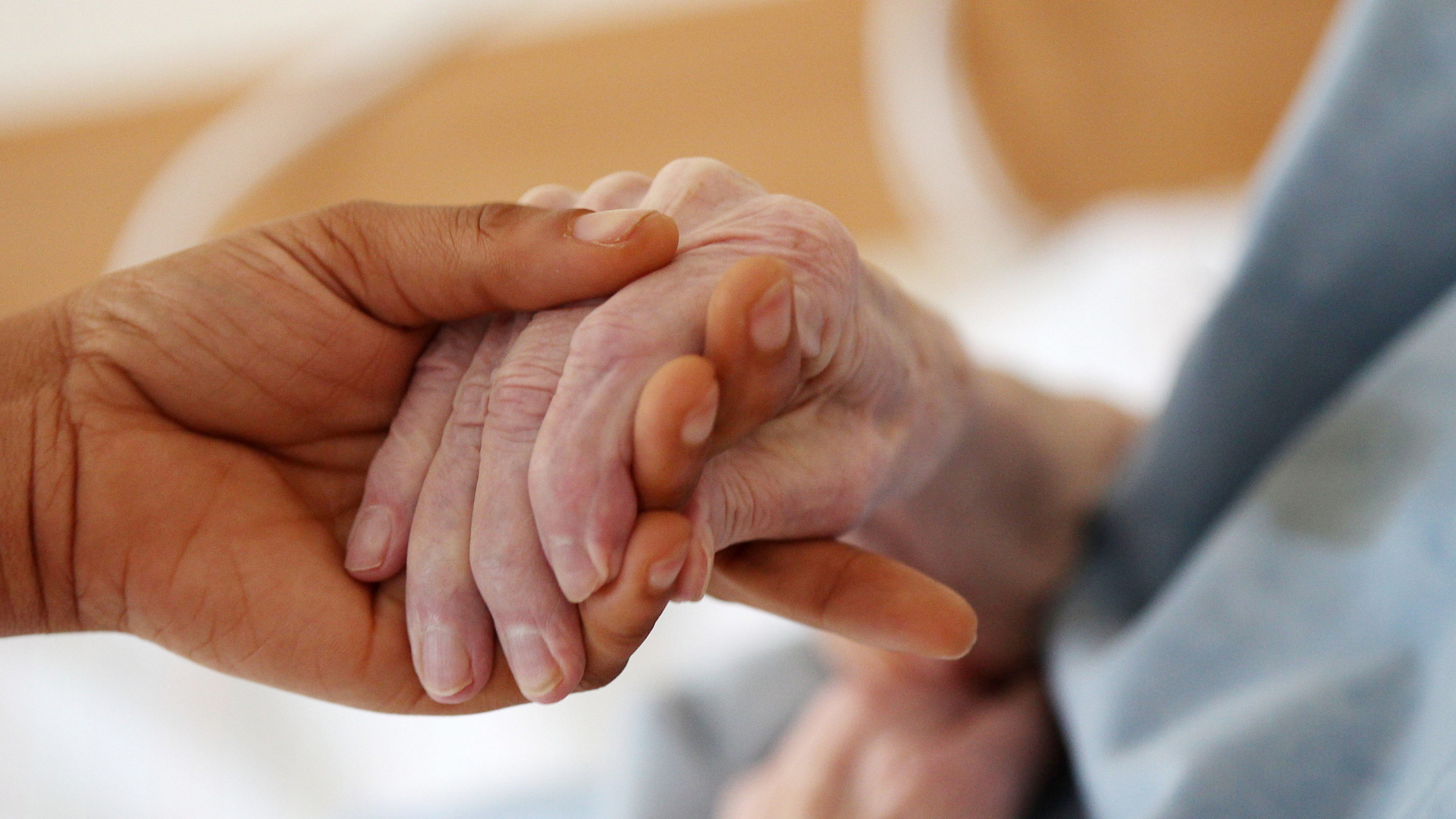 Eine Pflegerin hält die Hand einer Seniorin. | dpa