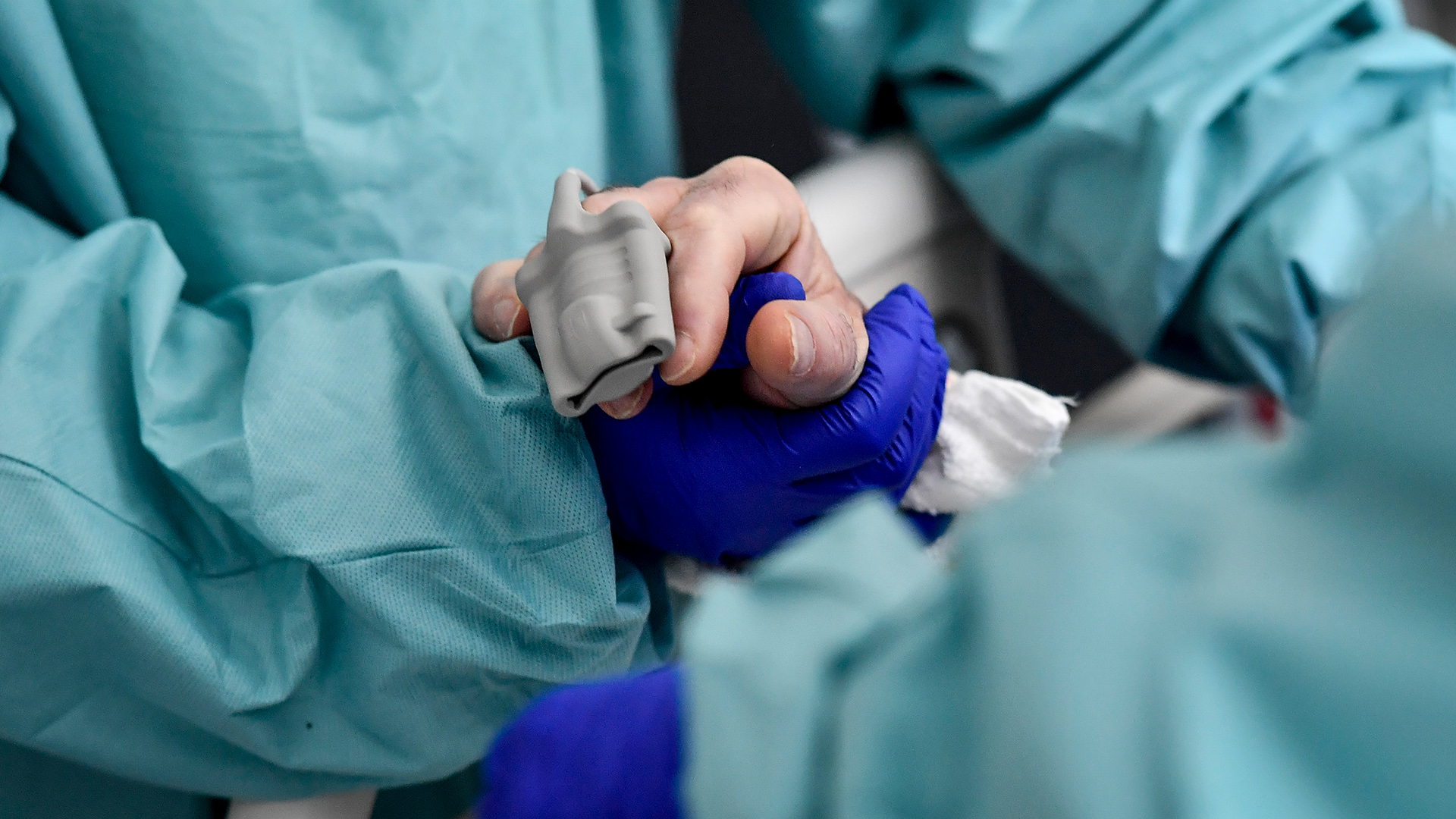 Ein Pfleger mit Handschuhe hält die Hand eines Covid-19-Patienten | dpa