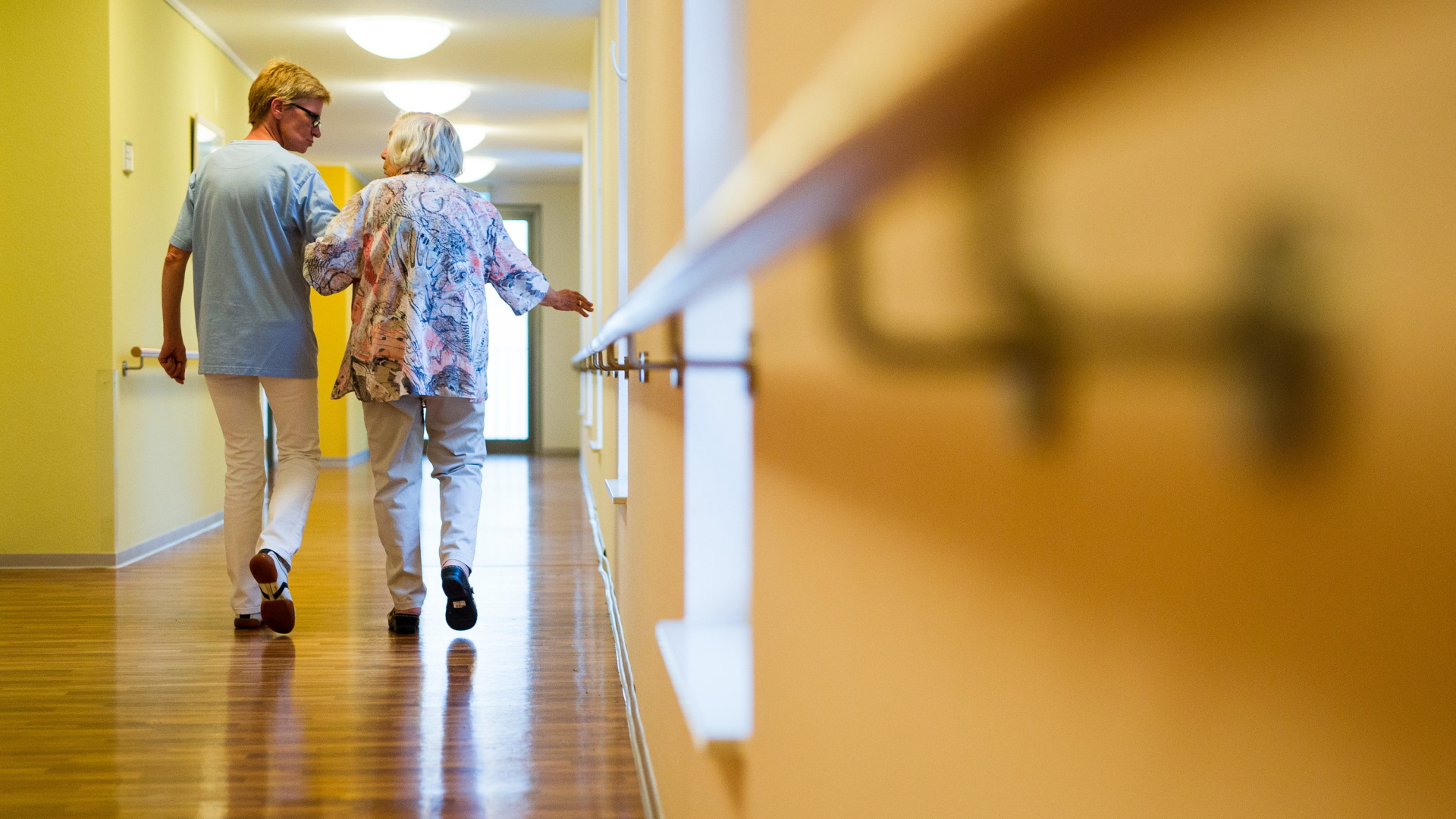 Eine alte Frau läuft bei einer Pflegerin untergehakt über einen Krankenhausflur. | Bildquelle: dpa