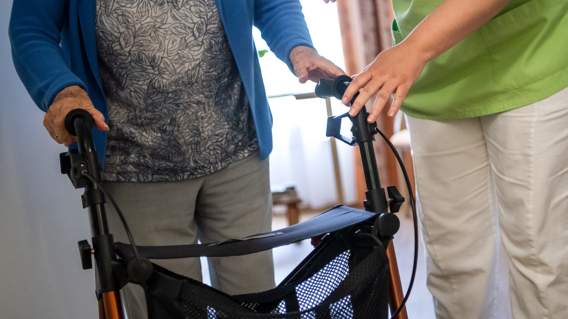 Eine Pflegefachkraft hilft einer Bewohnerin in einem Seniorenheim mit ihrem Rollator