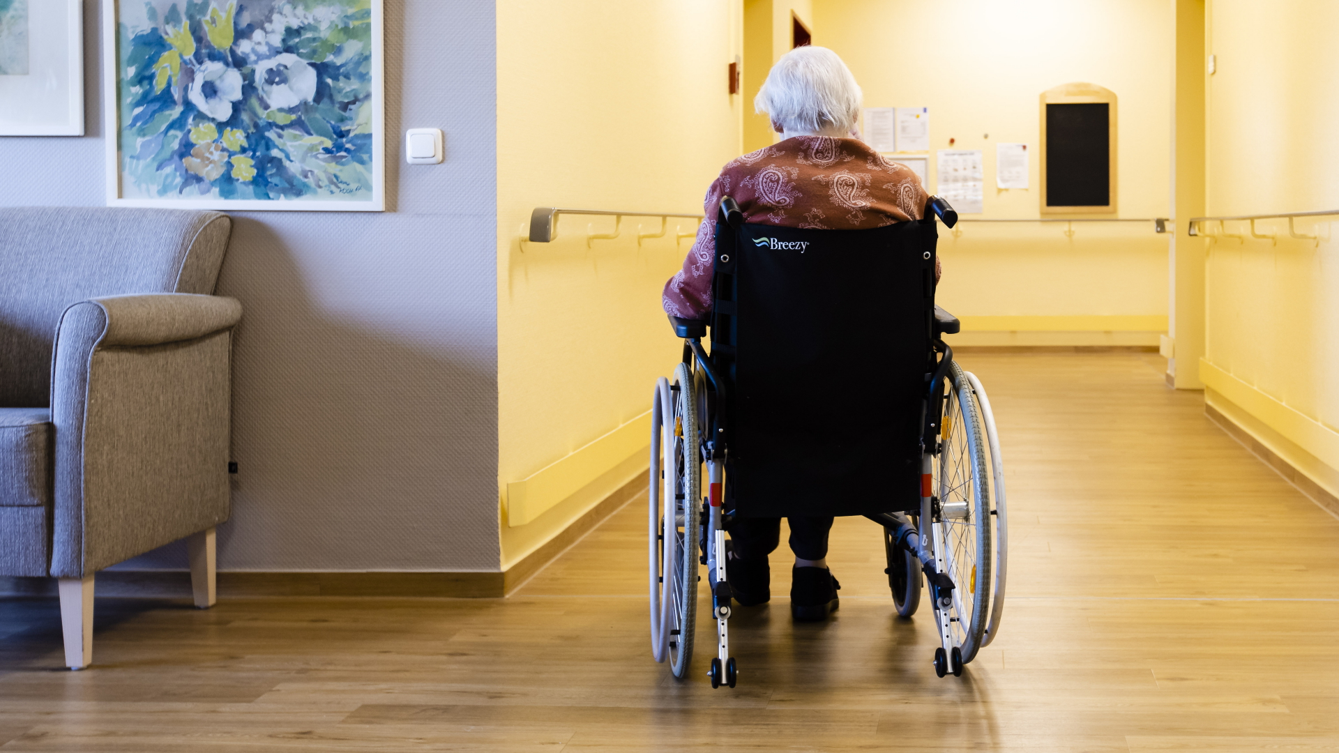 Eine ältere Frau sitzt mit demm Rücken zur Kamera in einem Rollstuhl in einem Pflegeheim in Kiel. | dpa