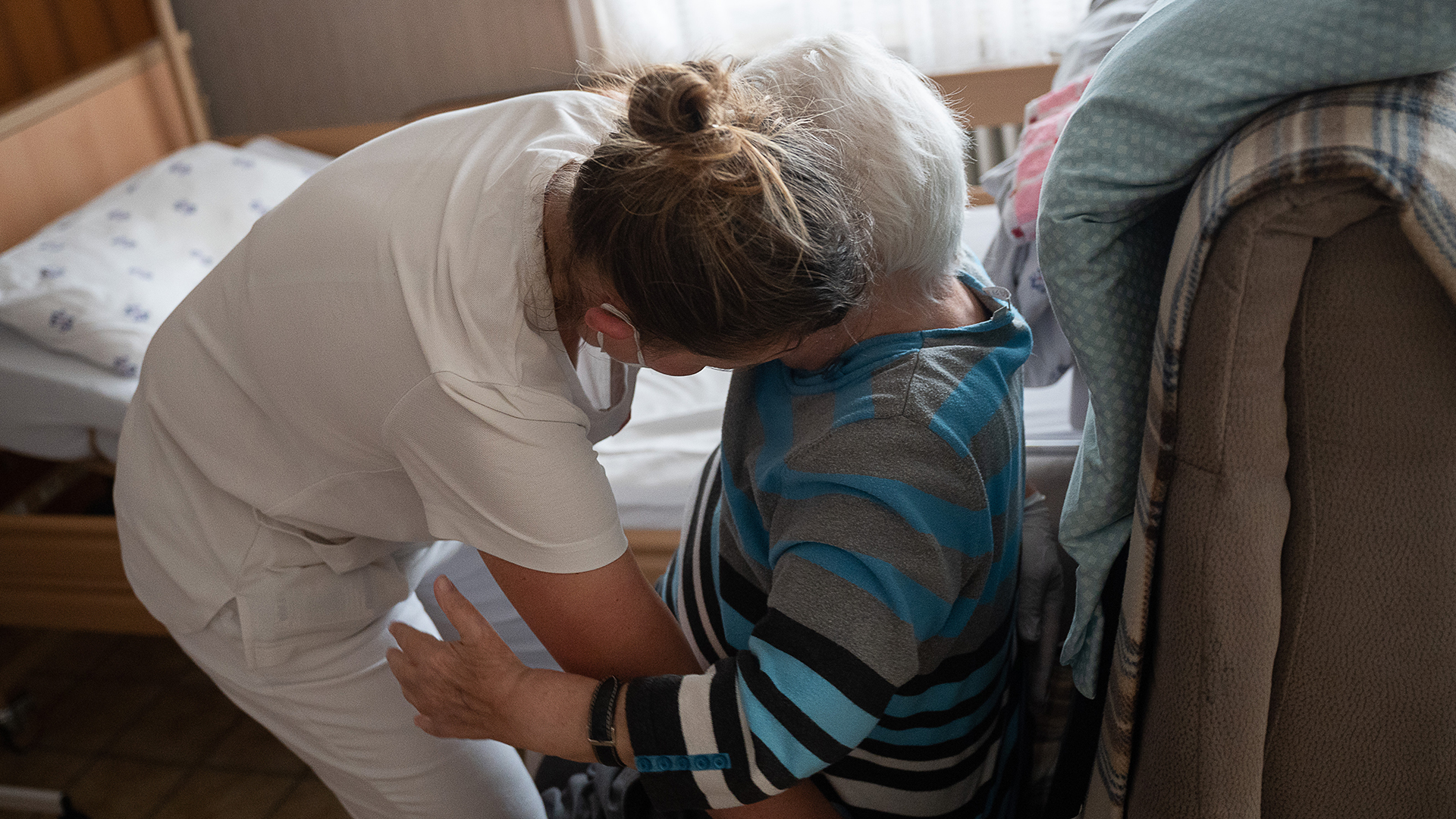 Eine Pflegefachkraft hilft in der ambulanten Pflege einer Frau beim Umsetzen vom Bett auf einen Sessel. | dpa
