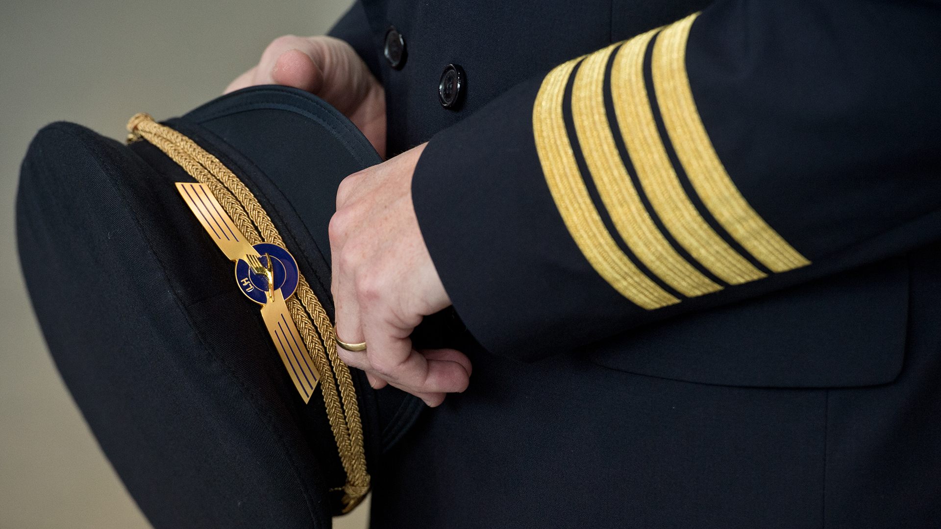 Ein Pilot der Lufthansa hält seine Pilotenmütze in der Hand.