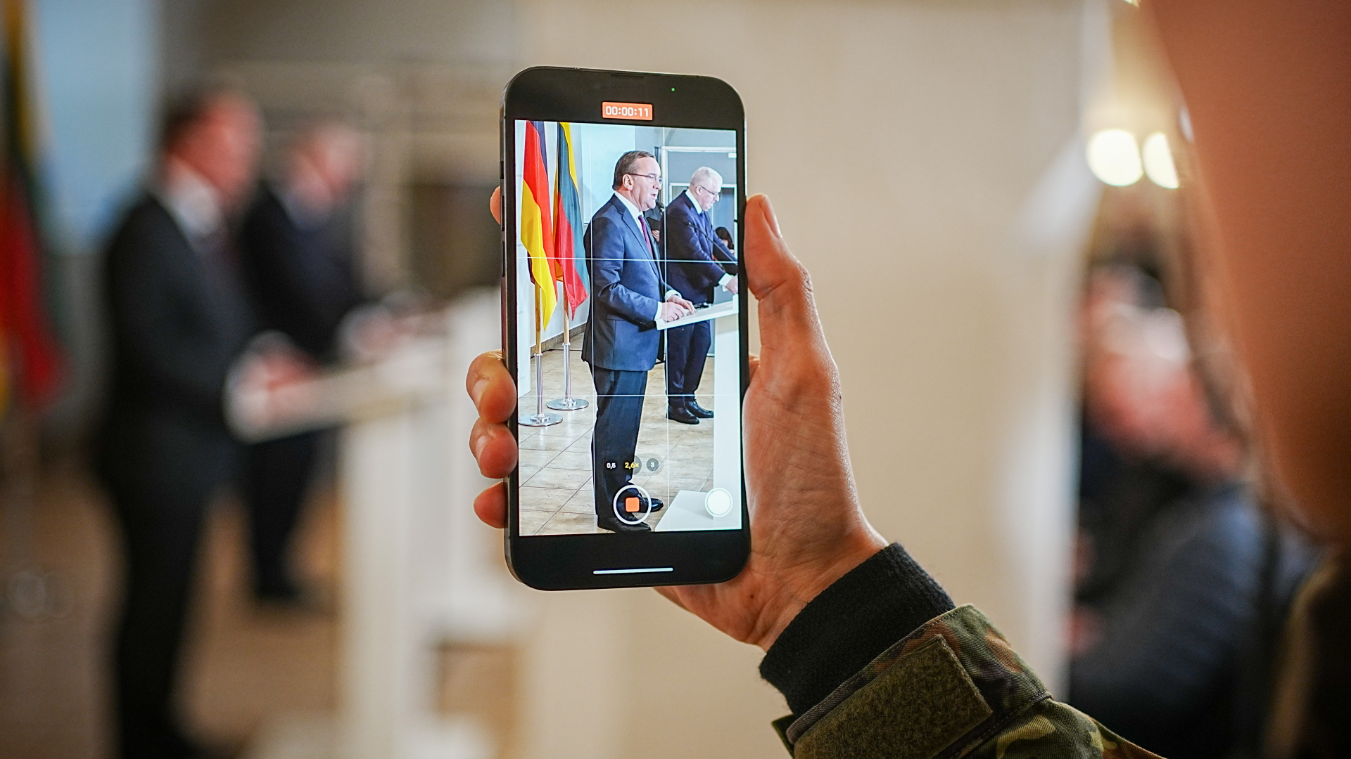 Boris Pistorius und Arvydas Anusauskas sind auf einem Smartphone während ihrer Pressekonferenz zu sehen.  | dpa