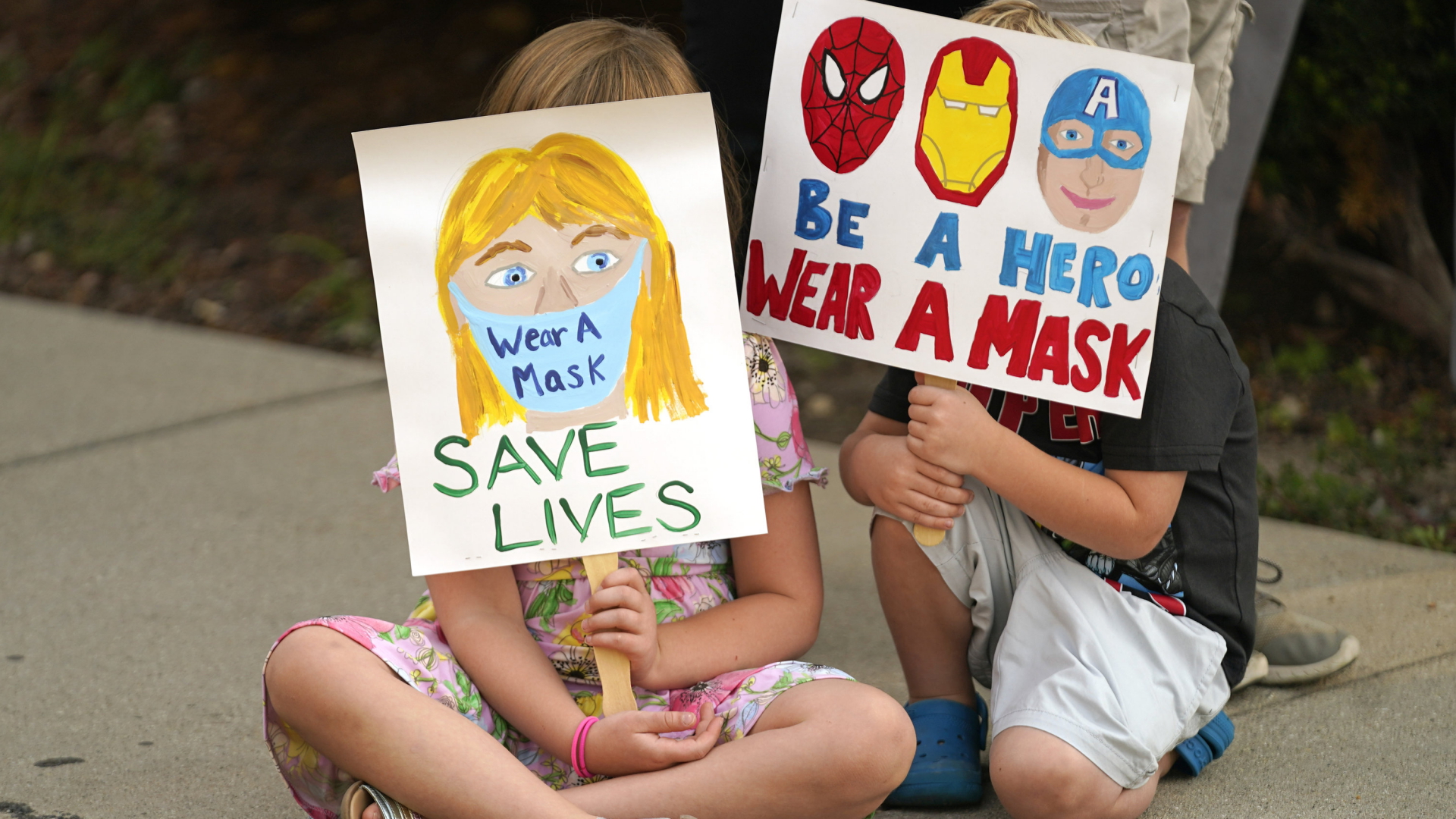 Zwei Kinder zeigen Plakate für eine Maskenpflicht an US-Schulen. | AP