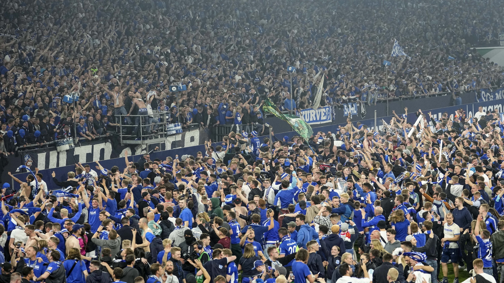 Fans von Schalke 04 feiern auf dem Rasen des Stadions in Gelsenkirchen den Wiederaufstieg ihres Vereins in die erste Fußballbundesliga.  | AP