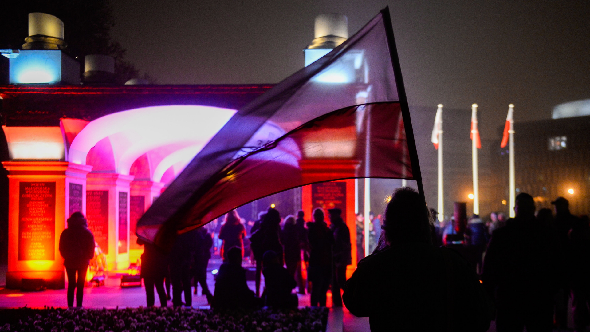 Polen, Warschau: Ein Mann hält eine polnische Flagge neben dem Grab unbekannter Soldaten hoch, während die neuen Statue des ehemaligen polnischen Präsidenten Kaczynski am Pilsudski-Platz enthüllt wird. Polen feiert am 11. November den 100. Jahrestag der Wiedererlangung seiner staatlichen Unabhängigkeit.  | Bildquelle: dpa