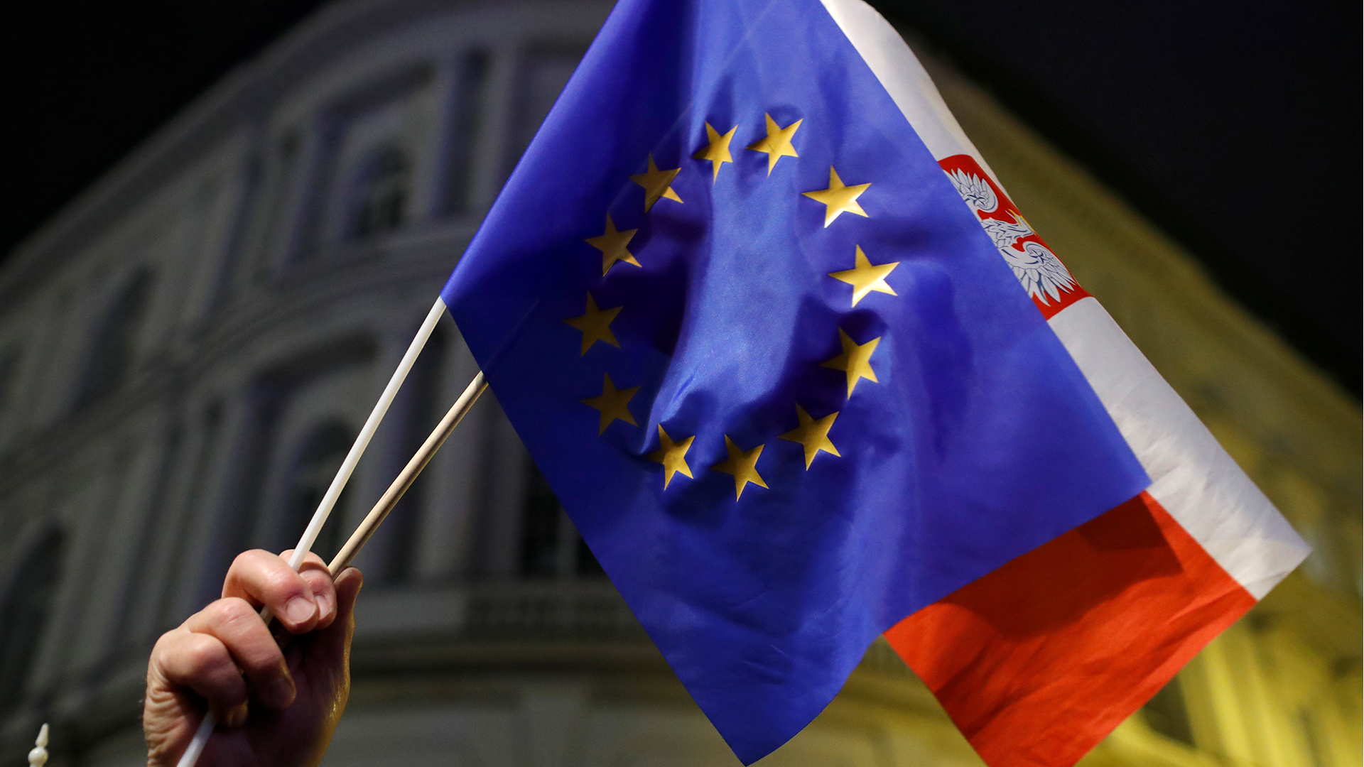 Hand hält die EU und die polnische Flagge