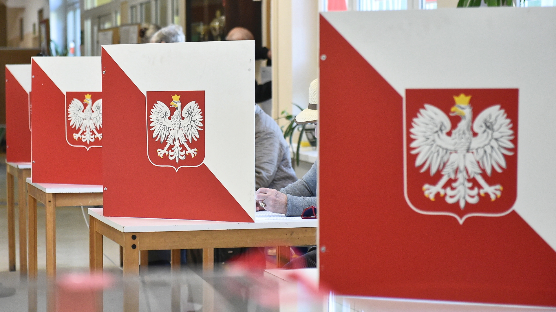 Menschen stimmen in Polen hinter Aufstellern in rot-weiß bei der Regionalwahl ab. | Bildquelle: MARCIN GADOMSKI/EPA-EFE/REX/Shut