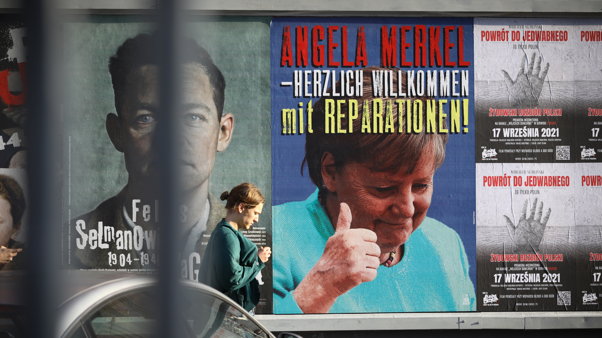 Ein Plakat mit der deutschsprachigen Aufschrift "Angela Merkel - herzlich willkommen mit Reparationen" hängt 2021 in Warschau. | picture alliance / NurPhoto