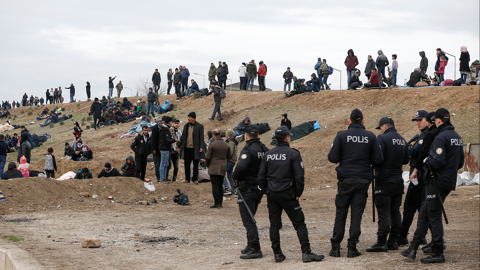 Türkische Polizisten stehen in der Nähe von Migranten nahe der türkisch-griechischen Grenze. | dpa