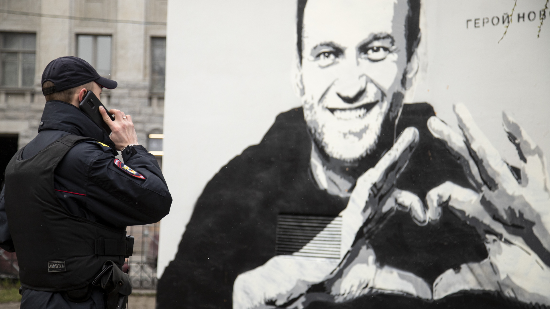 Ein Polizist steht vor einem Wandgemälde von Alexej Nawalny und telefoniert. | dpa