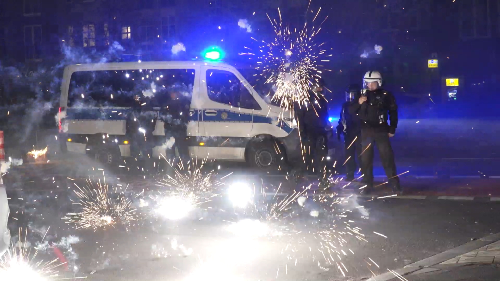 Polizeibeamte stehen in Berlin hinter explodierendem Feuerwerk. | dpa