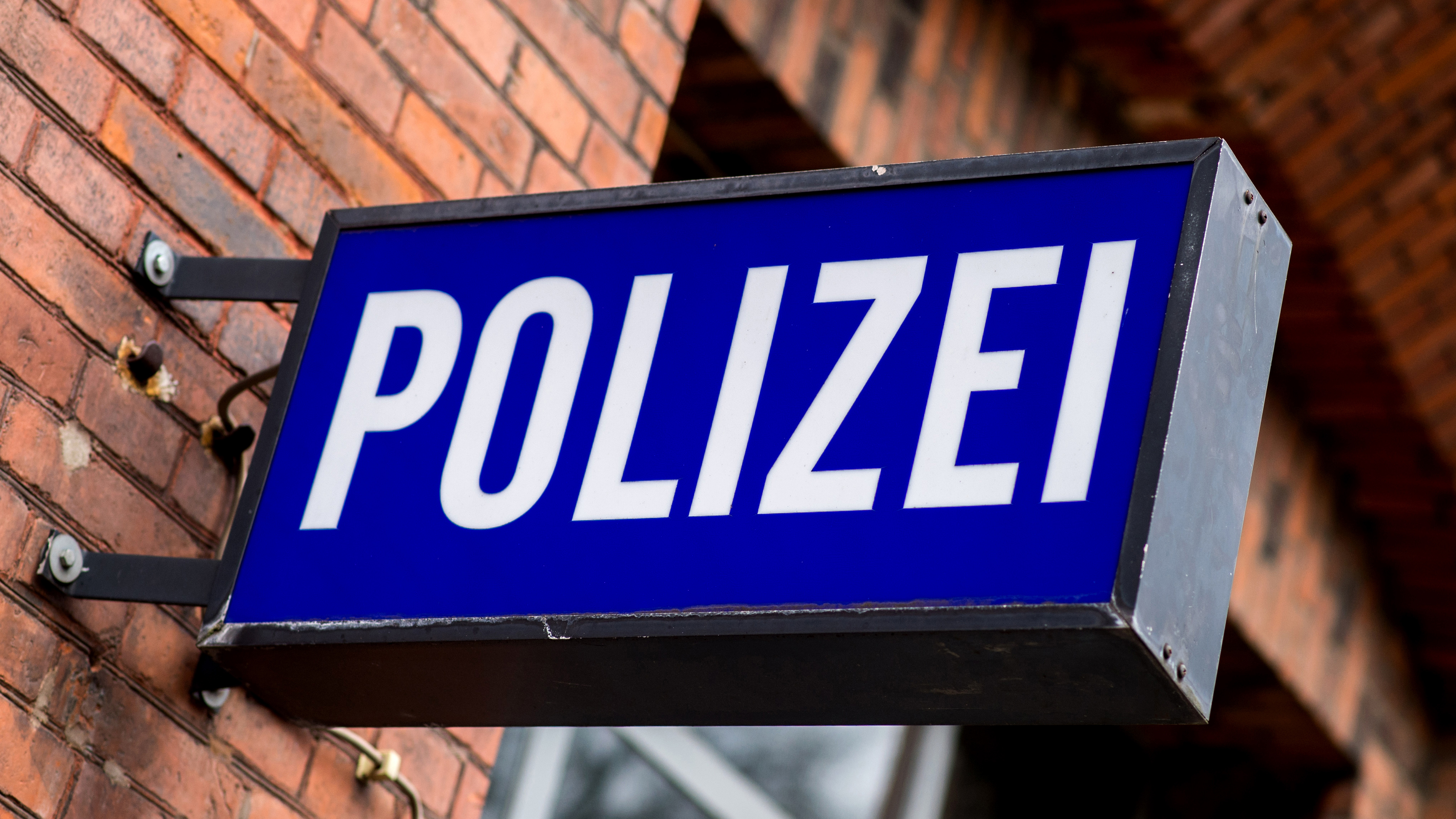 Der Schriftzug "Polizei" auf einem Schild am Gebäude einer Polizeiwache.