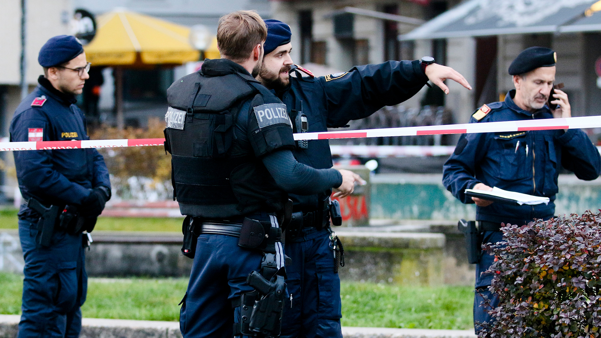 Polizisten stehen in Wien um ein Absperrband herum | AP