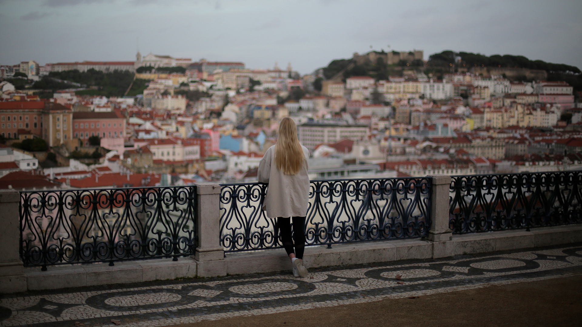 Eine Frau steht an einem Aussichtspunkt mit Blick auf Lissabons Altstadt. | dpa