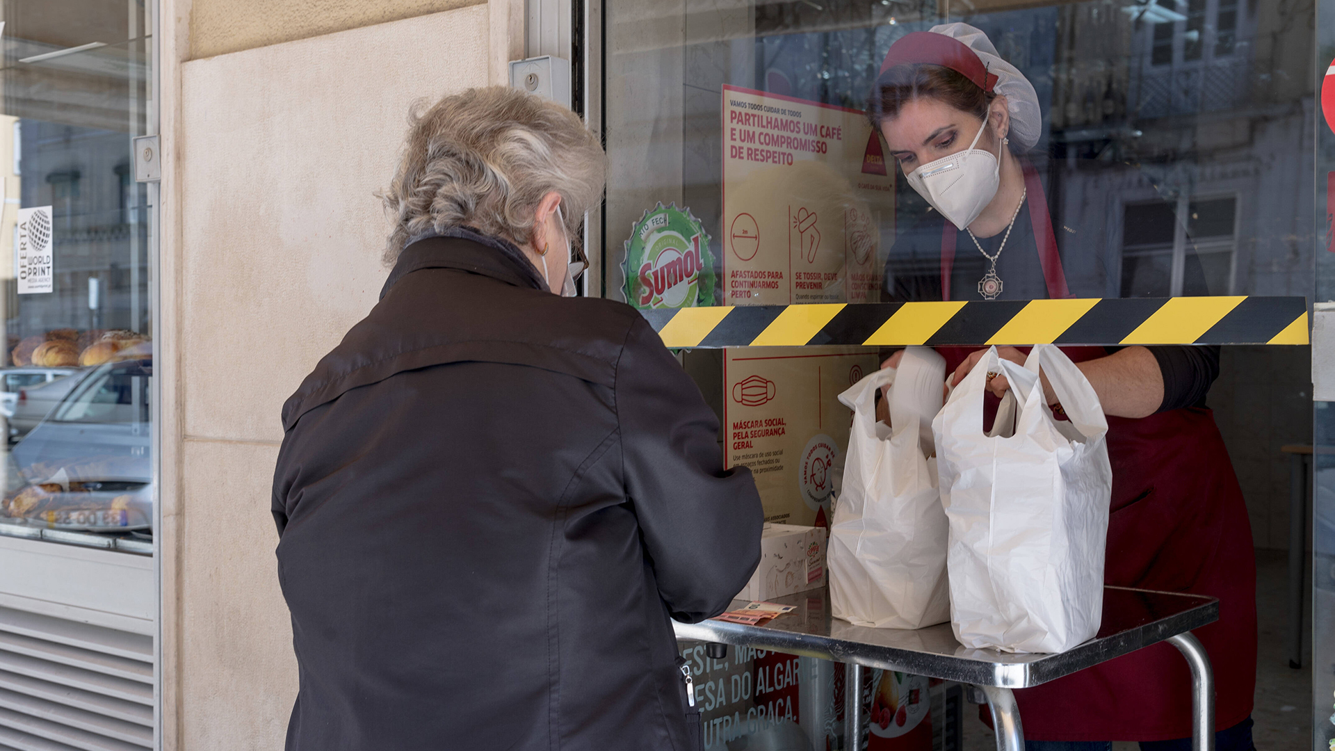 Eine Verkäuferin überreicht einer Kundin Einkaufstüten. | imago images/GlobalImagens