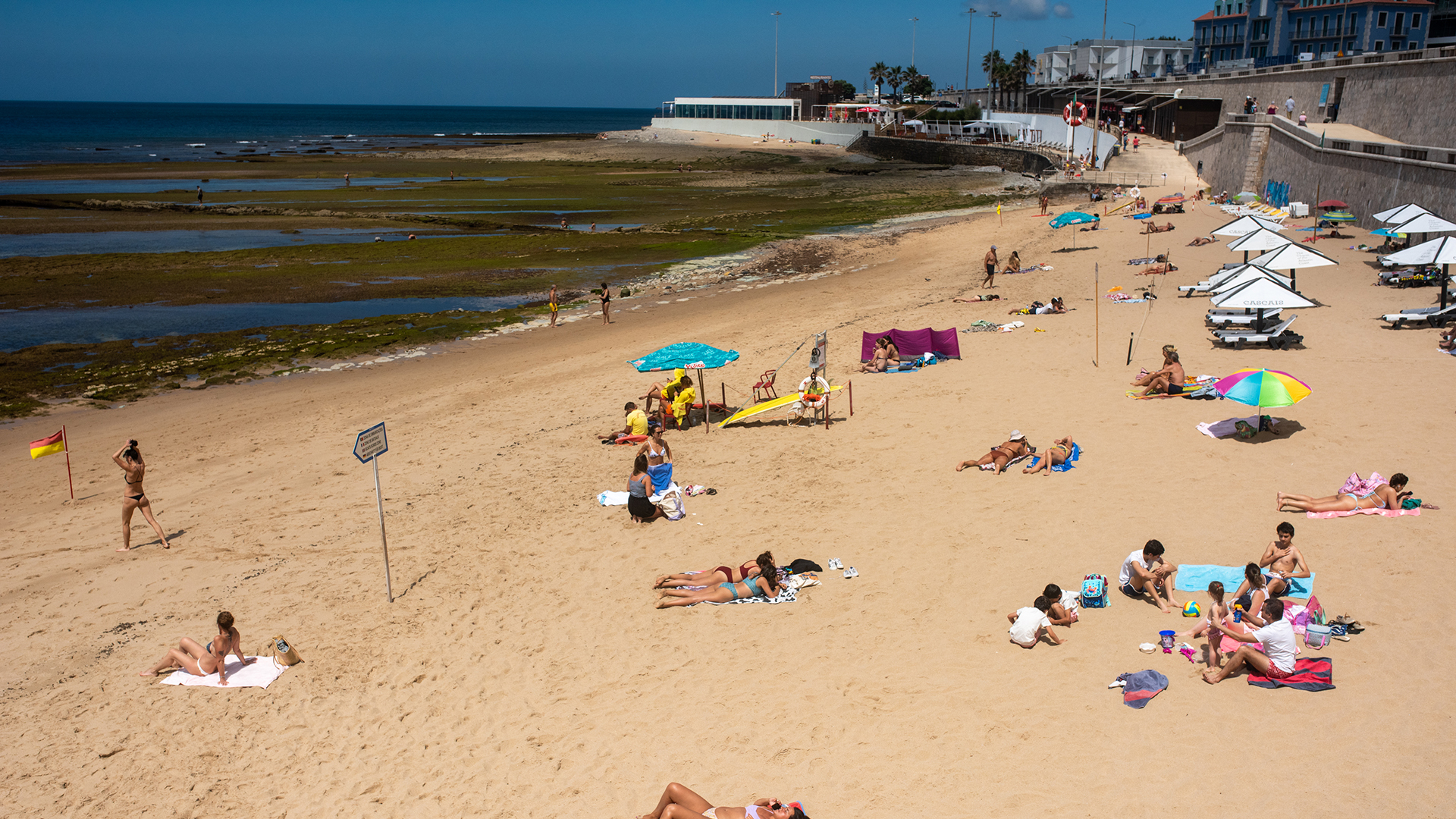 Touristen liegen am Strand von Parede in Lissabon. | dpa