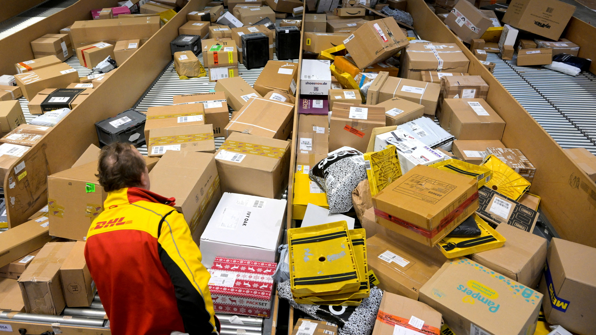 Ein Post-Mitarbeiter vor Laufbändern voller Pakete in einem Verteilzentrum in Hamburg (Archiv). | REUTERS