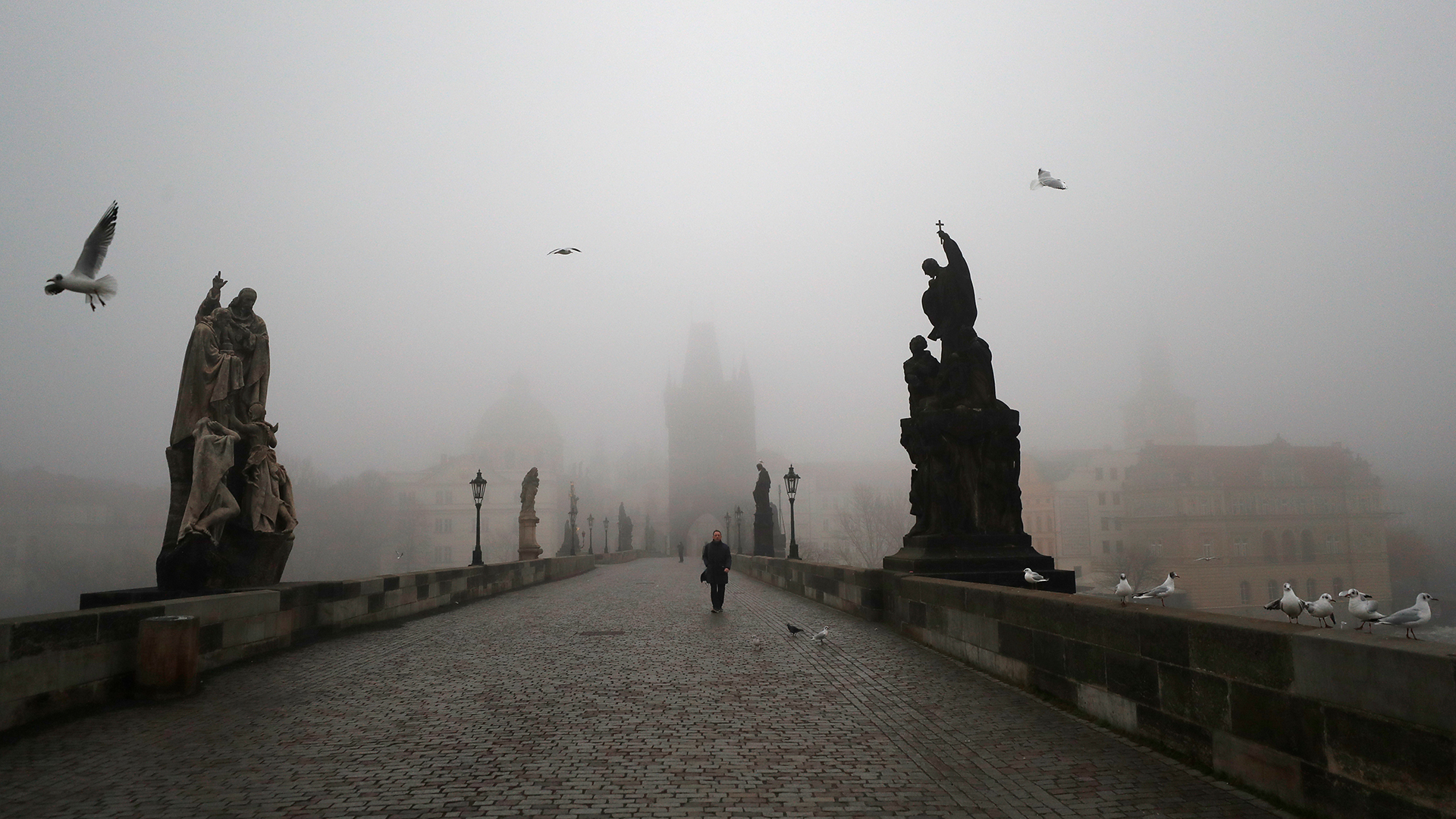 Ein Mann geht bei Nebel über die mittelalterliche Karlsbrücke im tschechischen Prag. | dpa