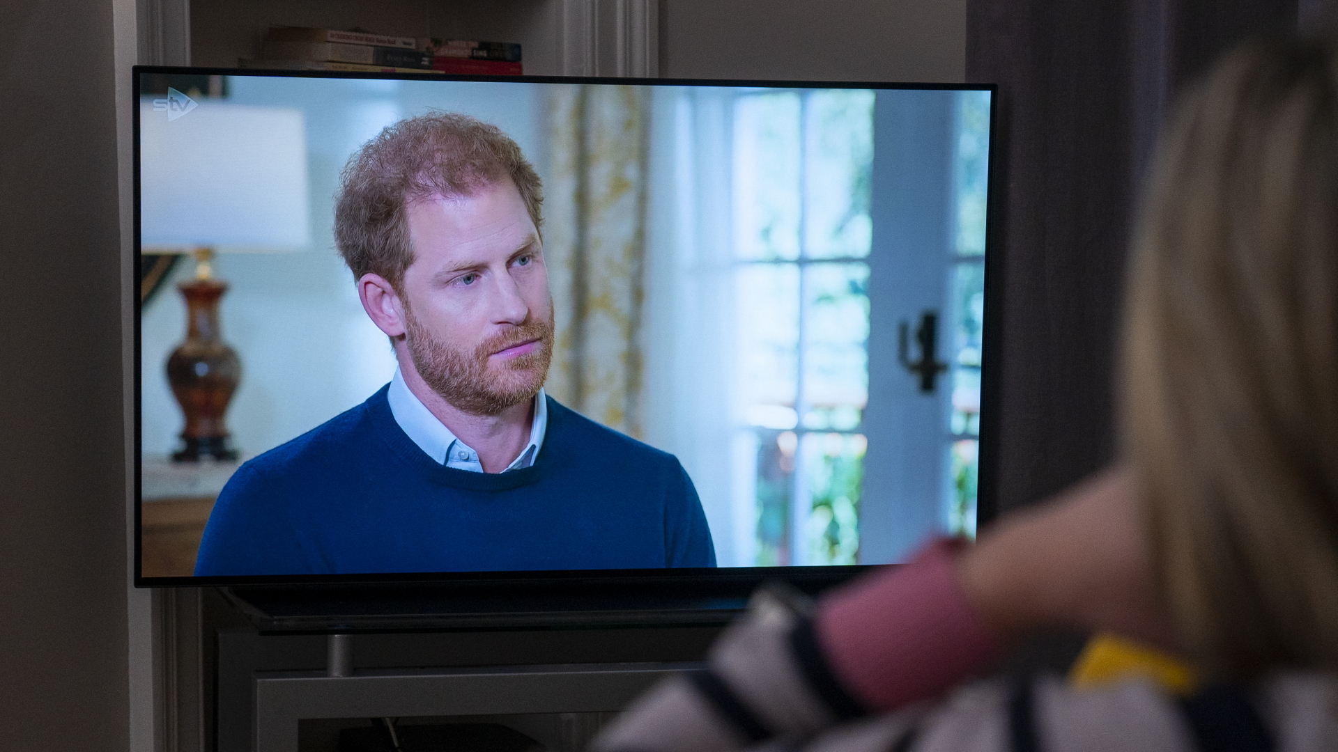 Eine Person beobachtet, wie Prinz Harry vom Sender ITV zu "Harry: Das Interview" interviewt wird.