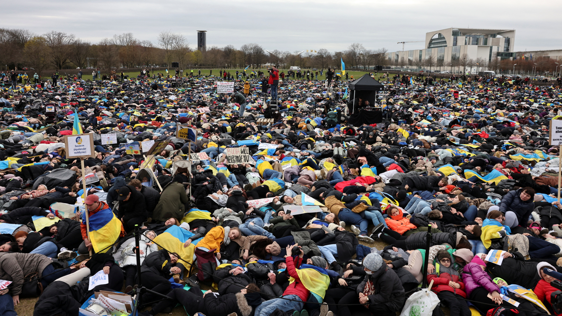 Menschen legen sich aus Protest gegen den Krieg in der Ukraine auf die Wiese vor dem Reichstagsgebäude in Berlin. | REUTERS