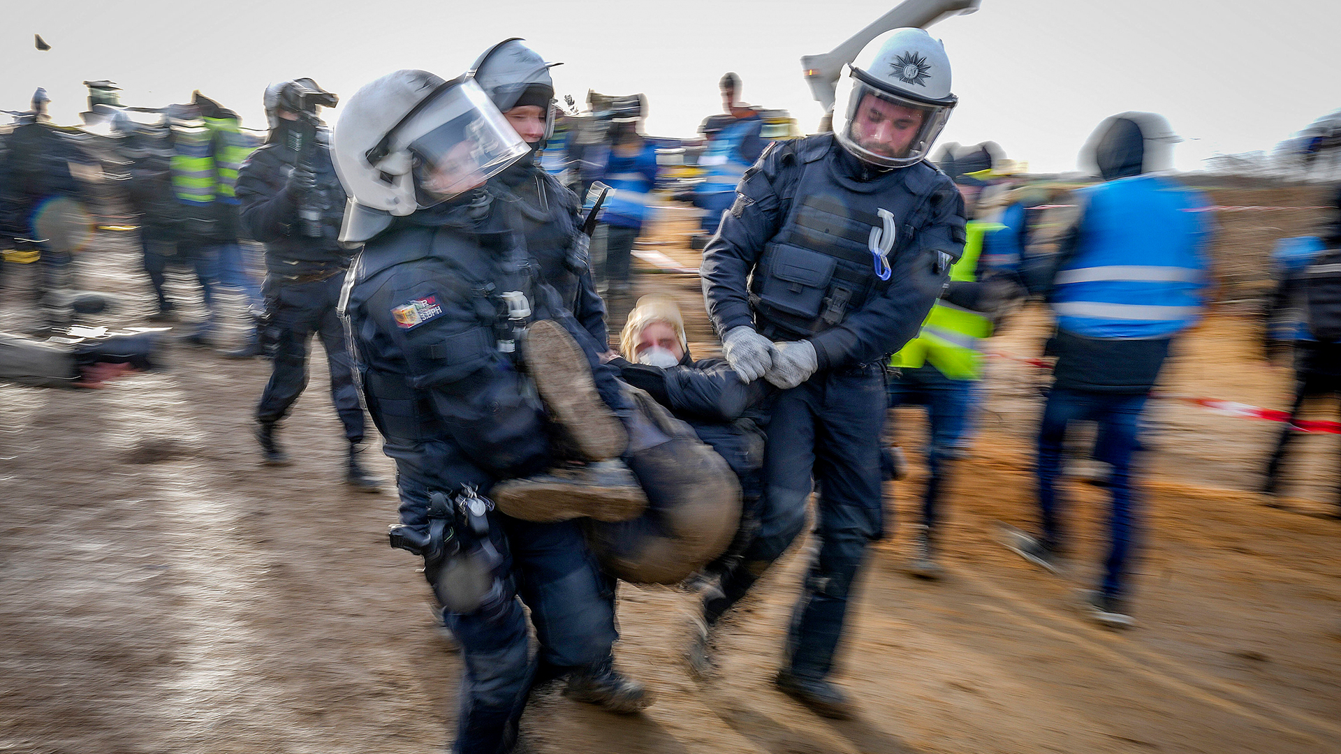 Polizeibeamte tragen einen Demonstranten zur Räumung einer Straße im Dorf Lützerath. | AP