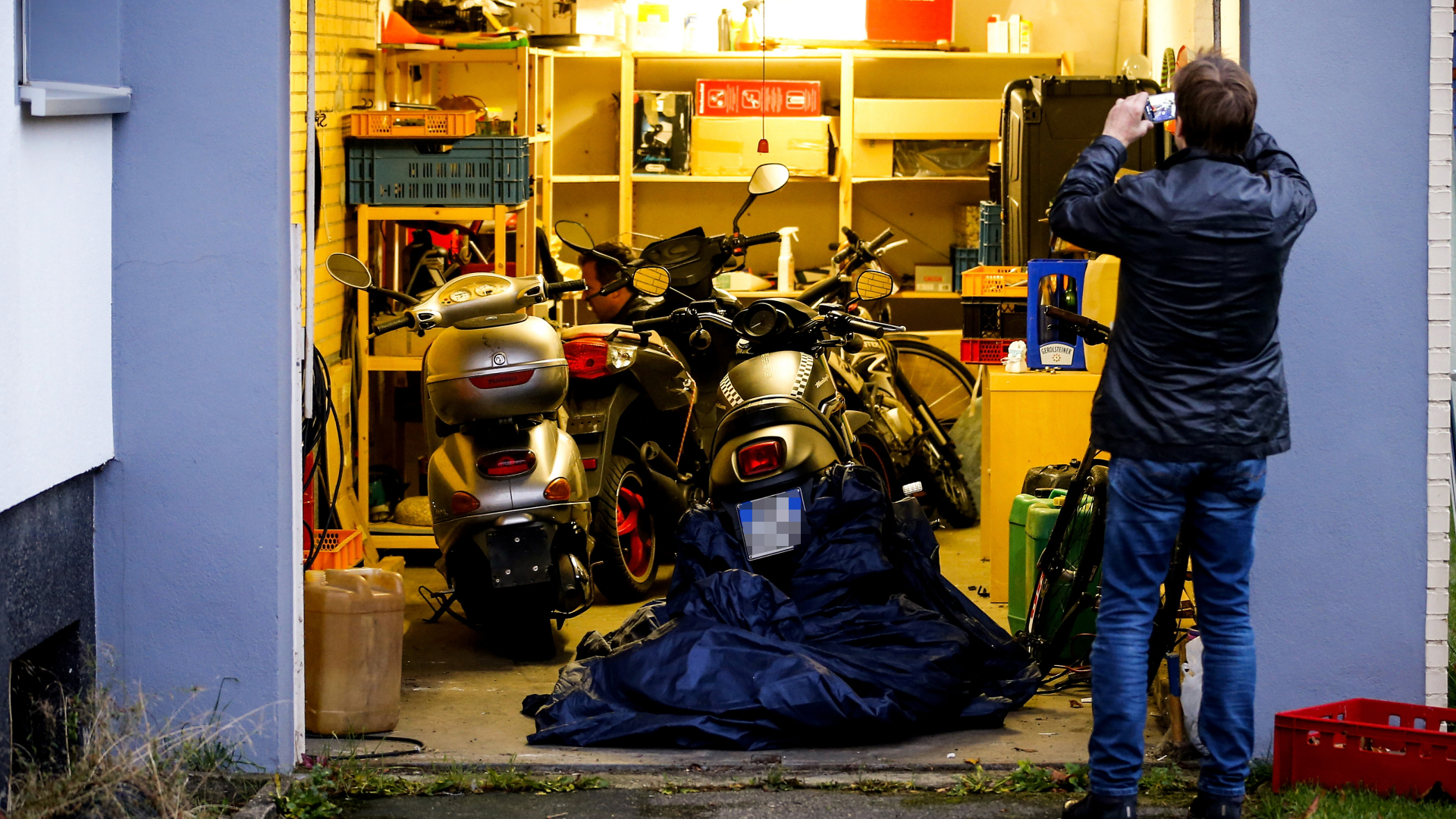Ein Polizist macht Fotos von einer Garage, in der Motorräder stehen | Bildquelle: SASCHA STEINBACH/EPA-EFE/REX/Shu