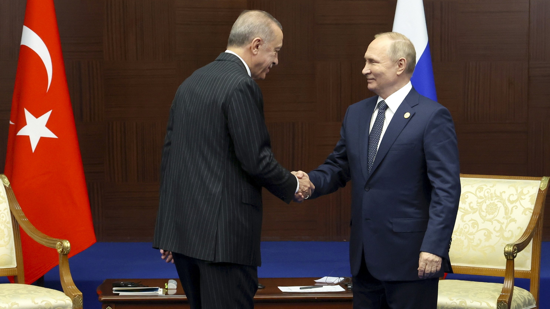 Der türkische Präsident Erdogan und Russlands Präsident Putin schütteln während eines Treffens in Kasachstan die Hände. | AP