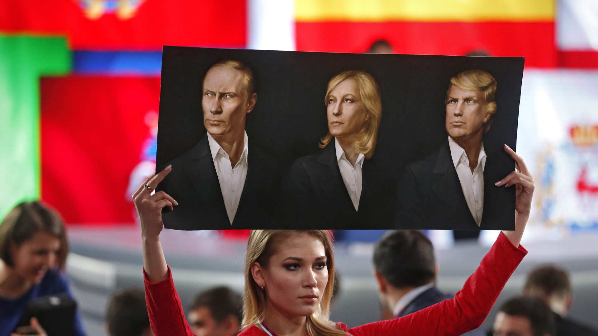 Eine Journalistin hält ein Plakat mit Putin, Le Pen und Trump bei einer Pressekonferenz in Moskau mit Putin. | dpa