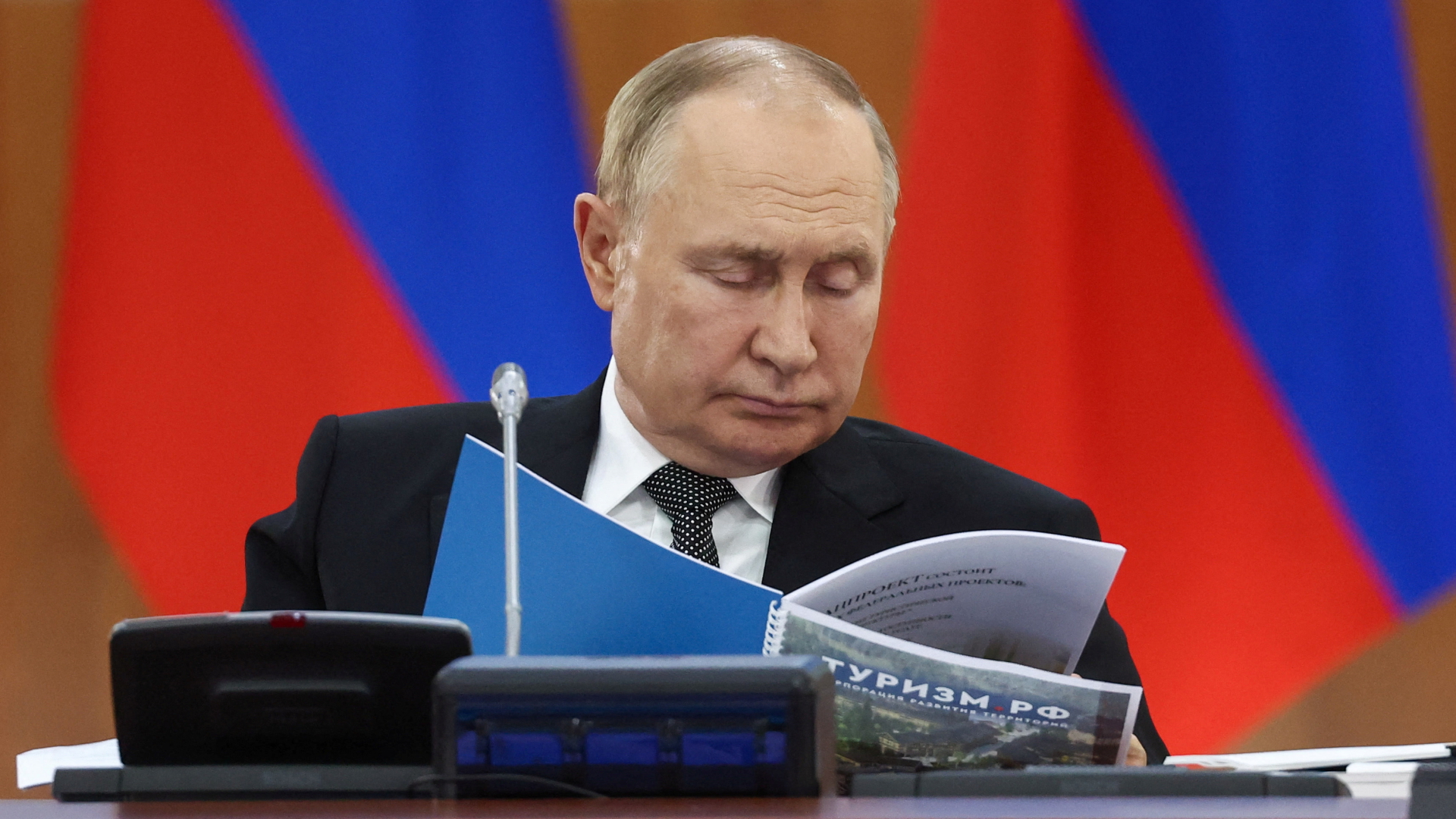 Wladimir Putin studiert eine Broschüre über den Tourismus in Russland | via REUTERS