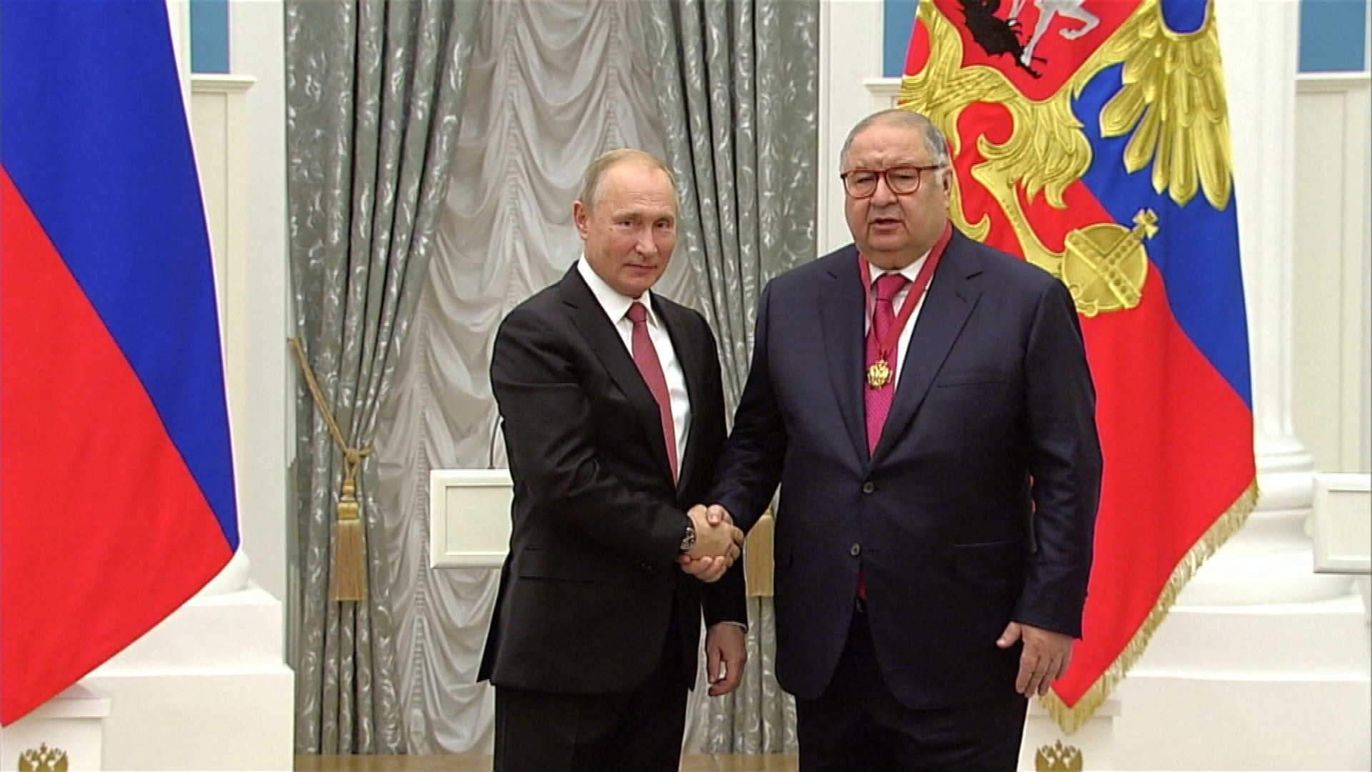 Wladimir Putin und Alisher Usmanov reichen sich die Hand. | BR