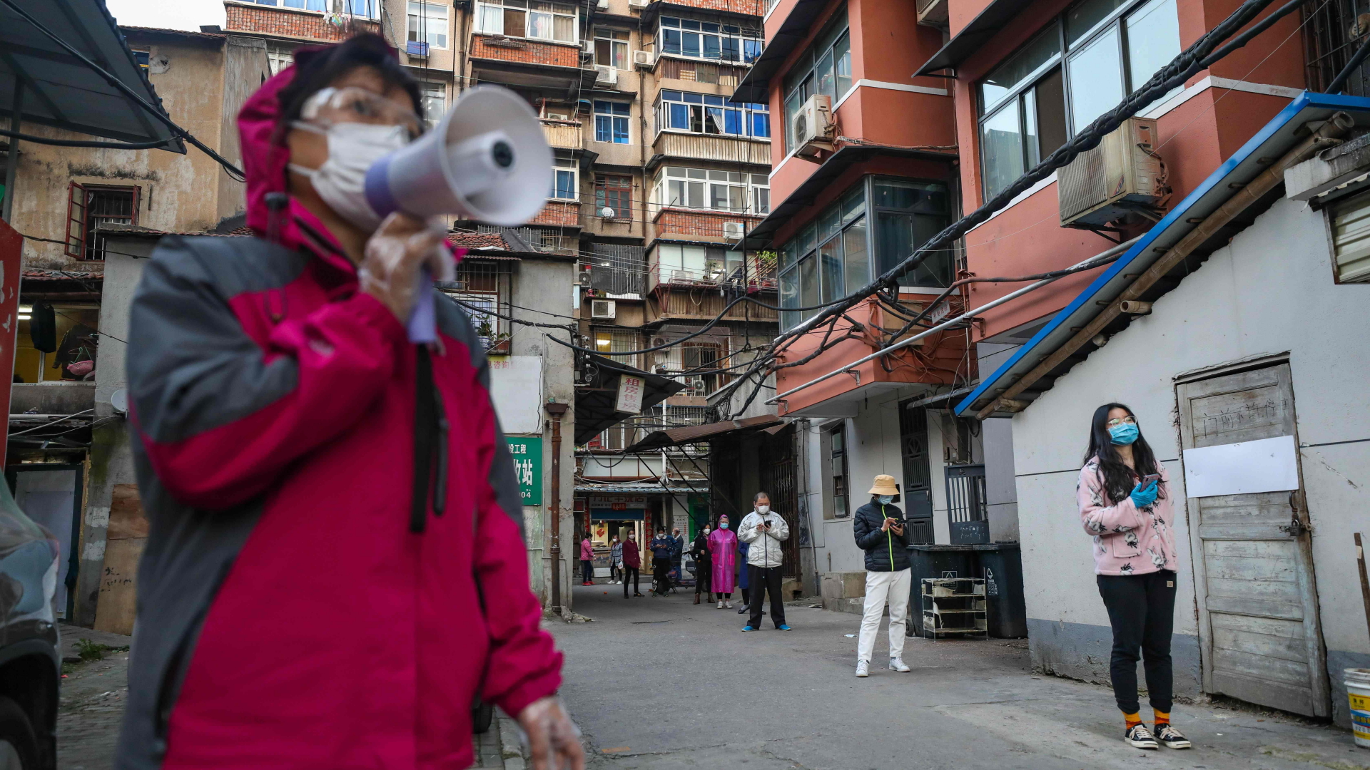 Menschen in Wuhan stehen mit weitem Abstand Schlange. | AFP