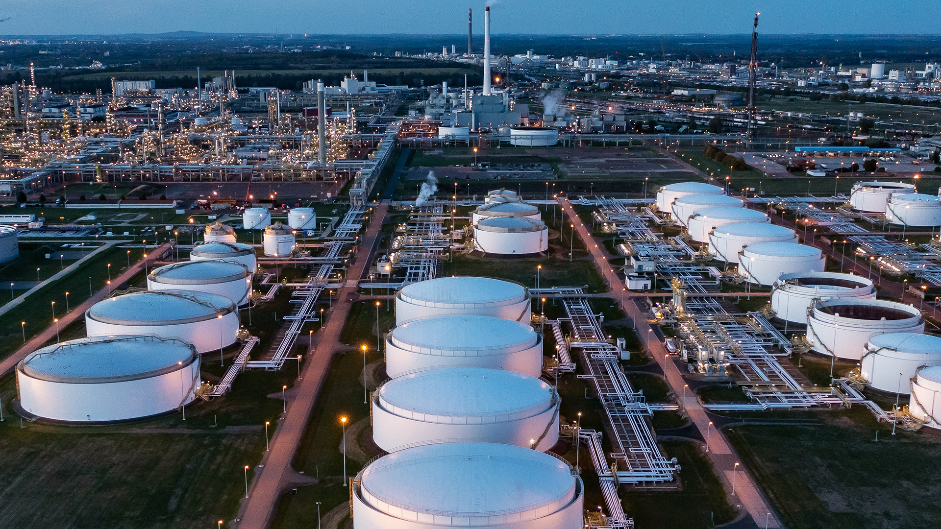 Hinter dem beleuchteten Tanklager ragen die Anlagen der Total-Raffinerie und des Chemieparks in die Höhe. | dpa