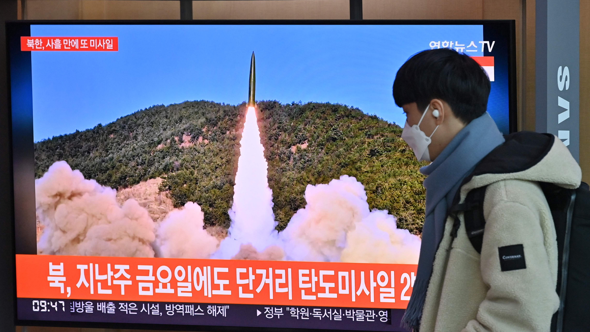 Ein Mann läuft in der südkoreanischen Hauptstadt Seoul an einem Bildschirm vorbei, der einen Raketentest Nordkoreas zeigt. | Bildquelle: AFP
