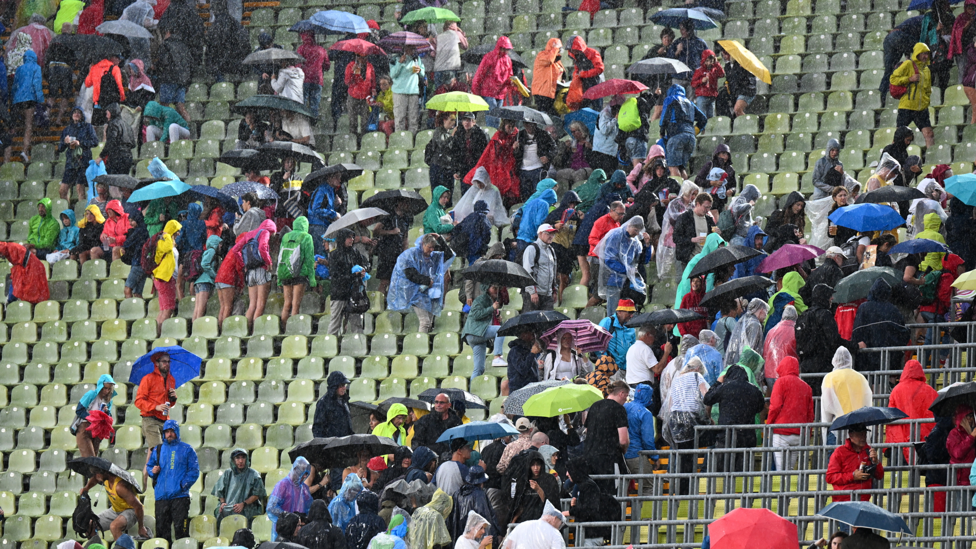 Zuschauer mit Regenschirmen verlassen die Plätze. Wegen einer Unwetterwarnung wurden die Wettkämpfe der Leichtathletik-EM in München unterbrochen. | dpa