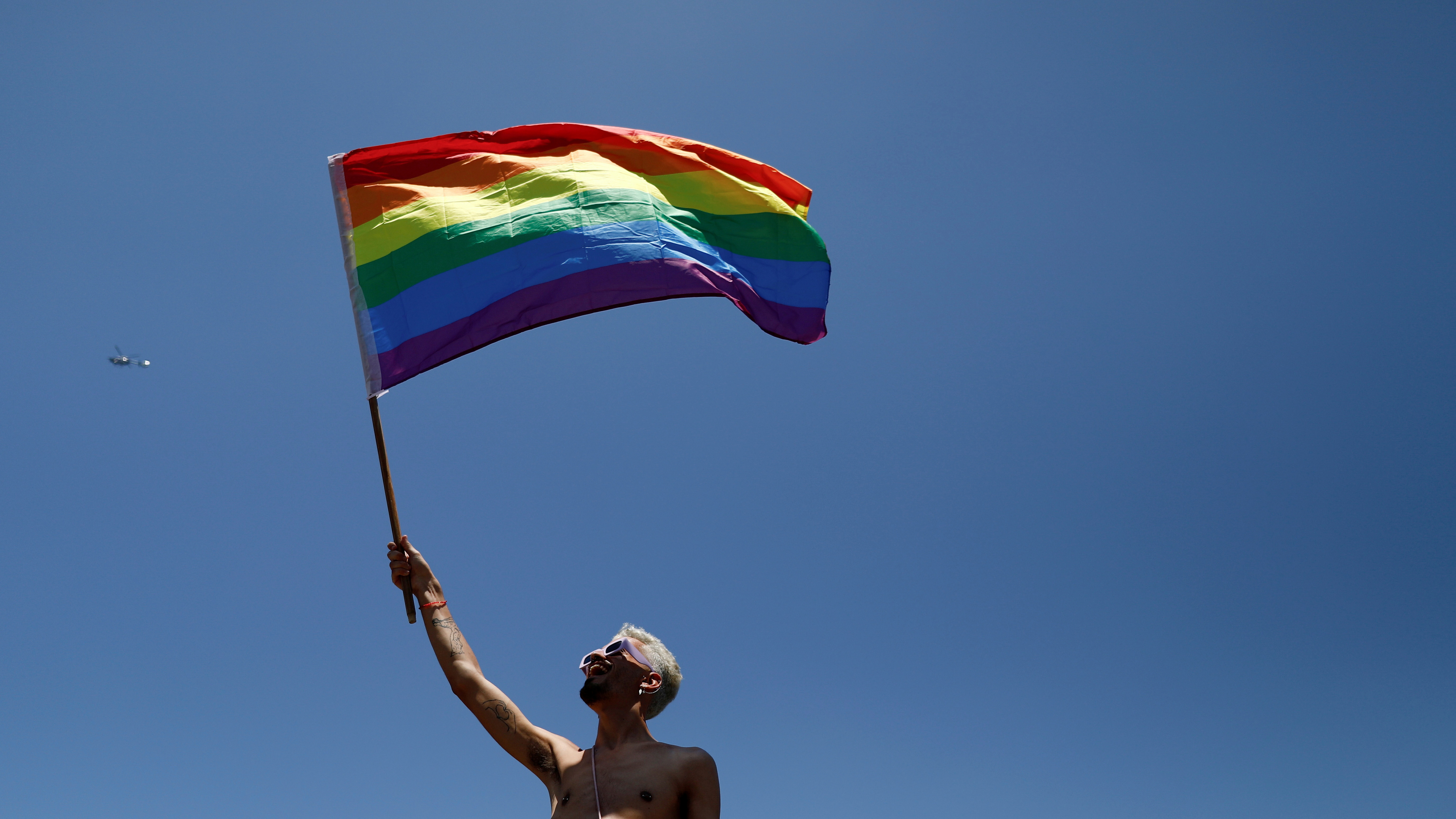 Eine Person hält eine Regenbogenfahne in die Luft. | REUTERS