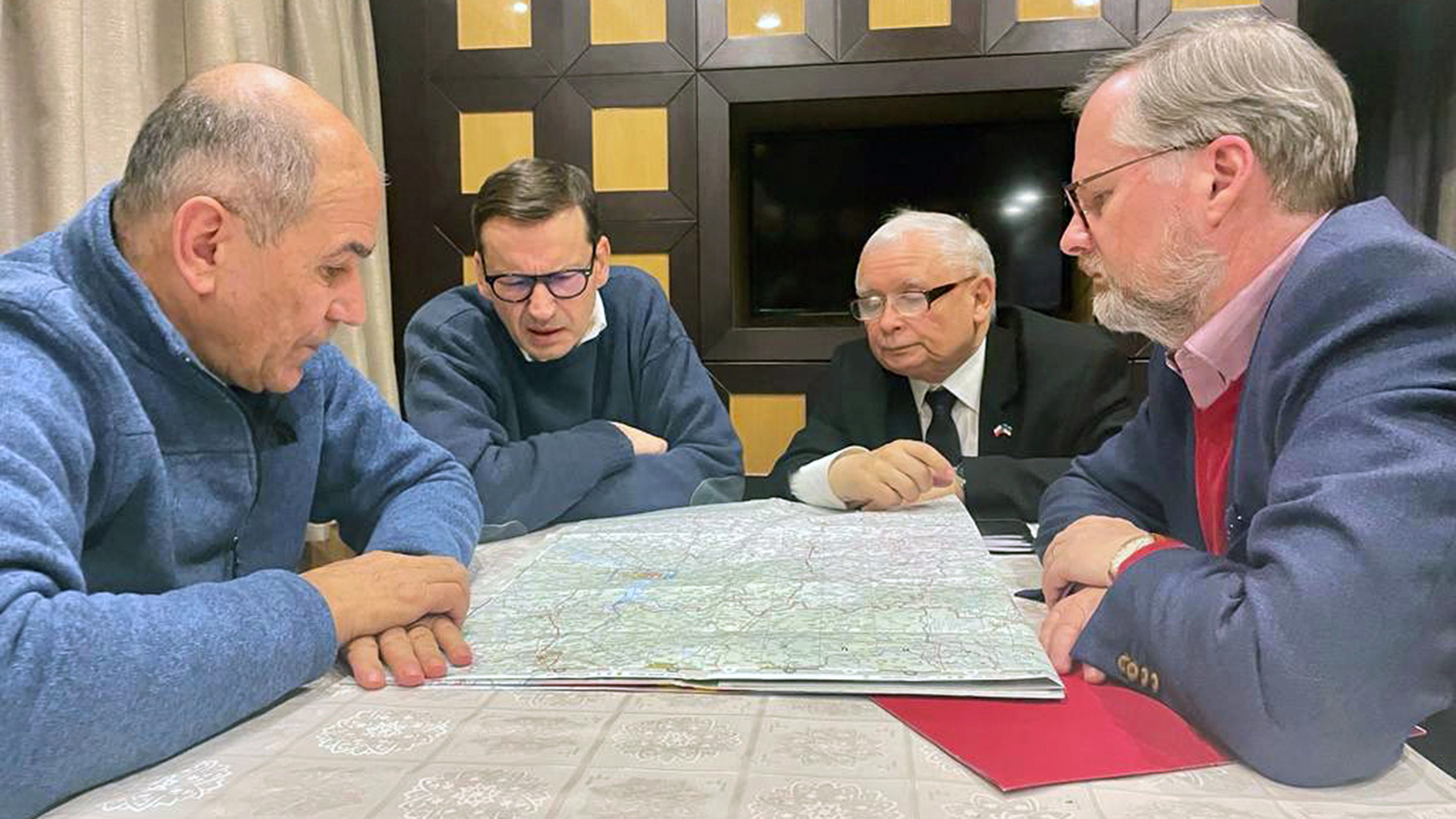 Die Regierungschefs von Polen, Tschechien und Slowenien sitzen im Zug nach Kiew über eine Karte gebeugt an einem Tisch | dpa