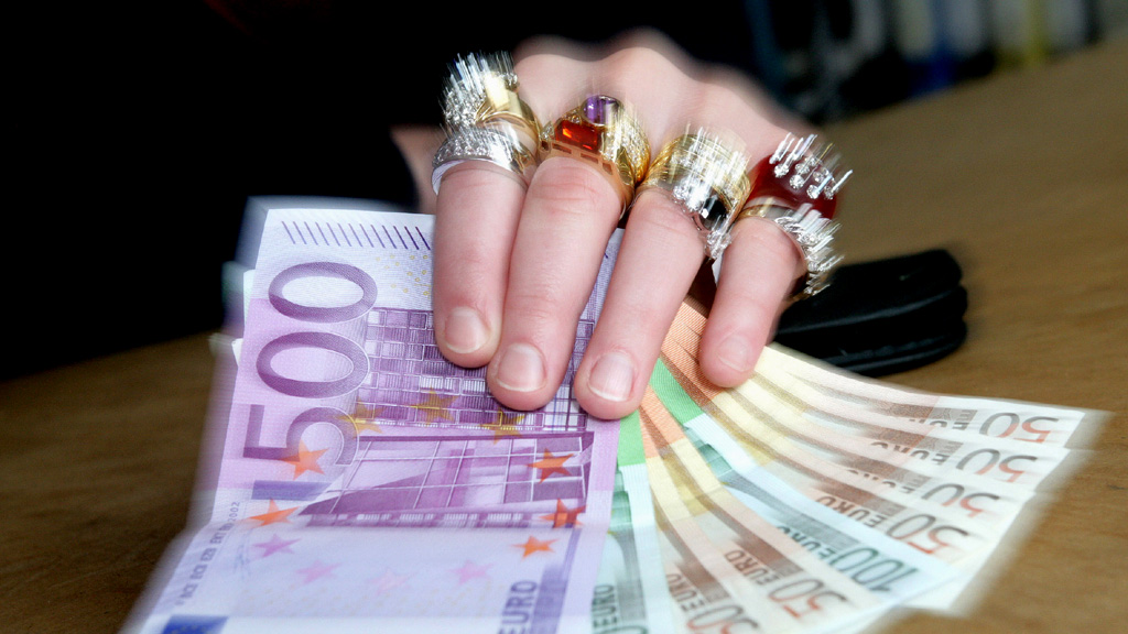 Eine Hand mit Ringen hält Euro-Scheine