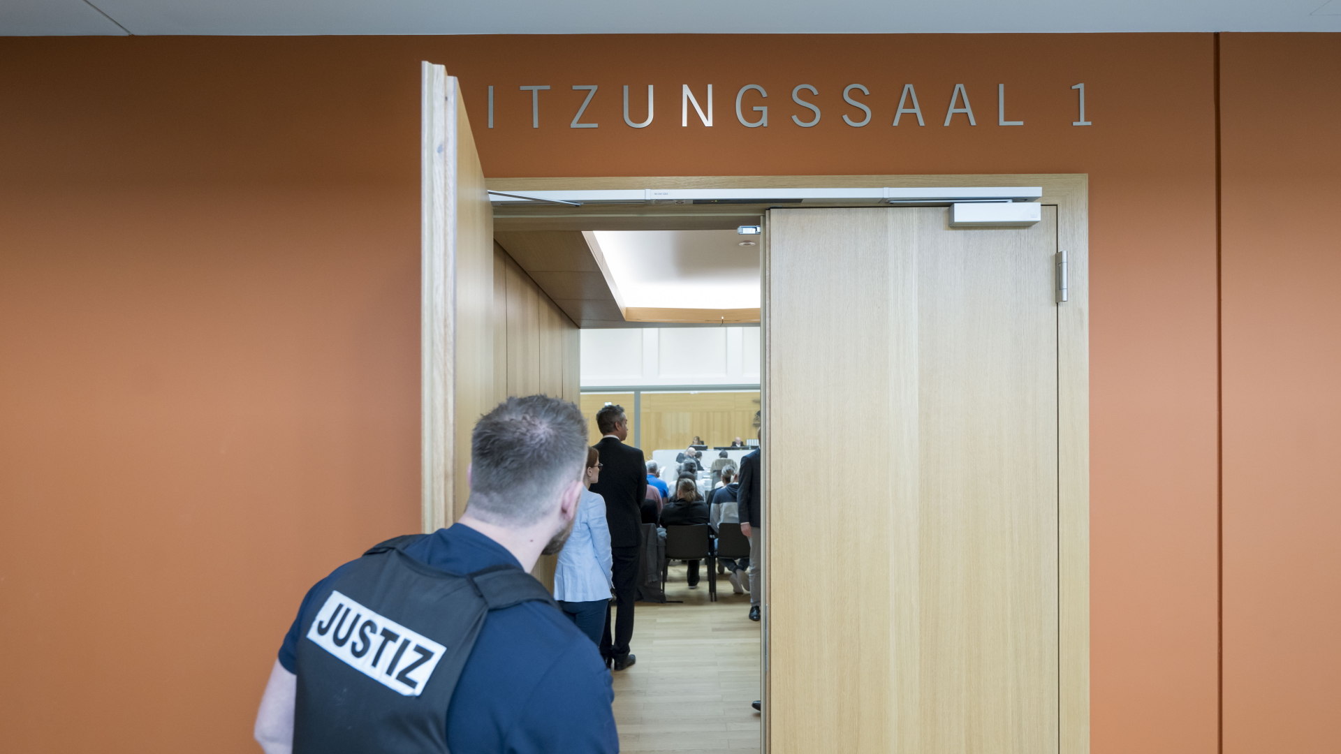 Ein Justiz-Beamter hält die Tür zum Sitzungsaal 1 des Oberlandesgerichts Stuttgart offen.